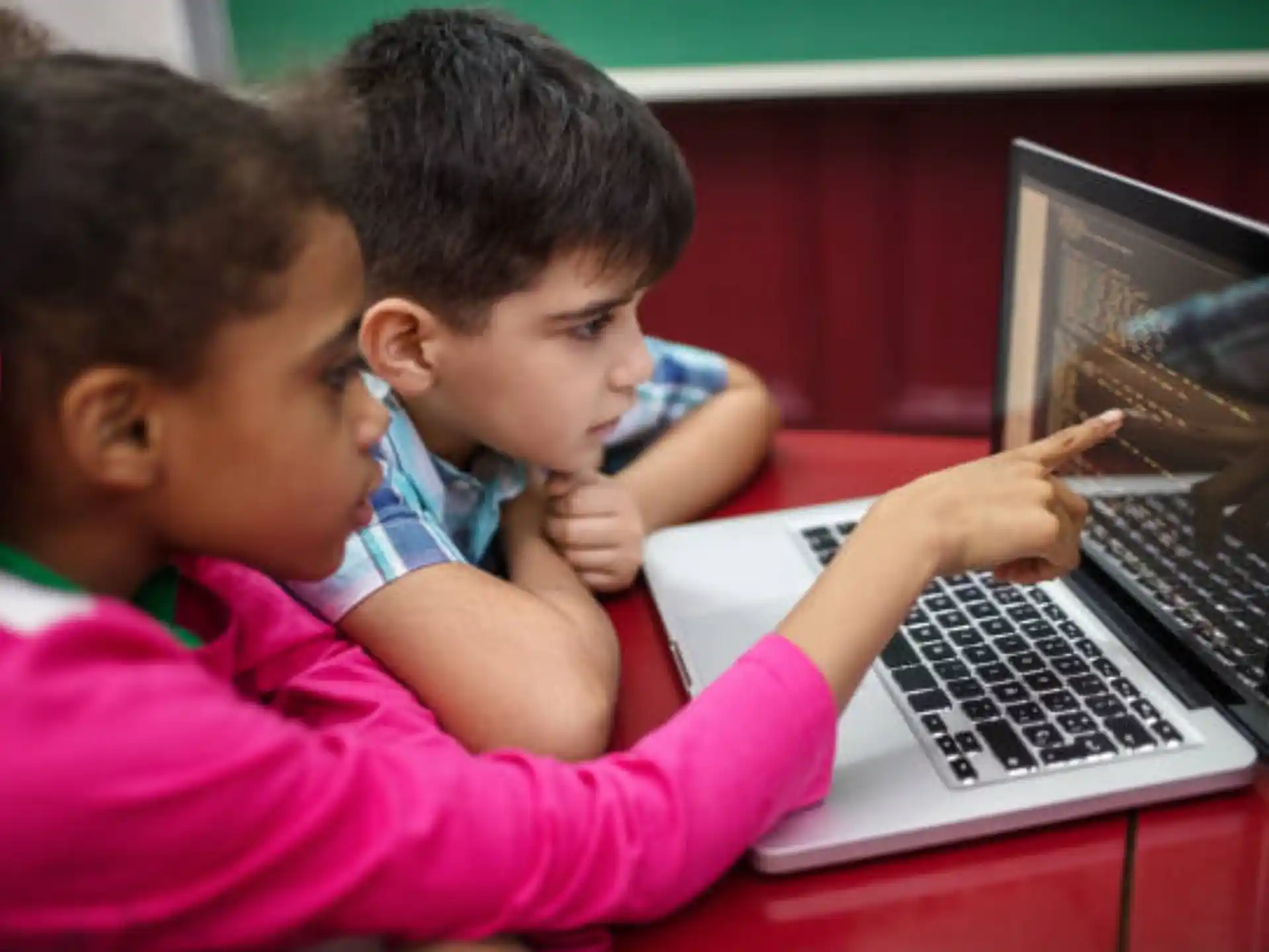a couple of children looking at a laptop