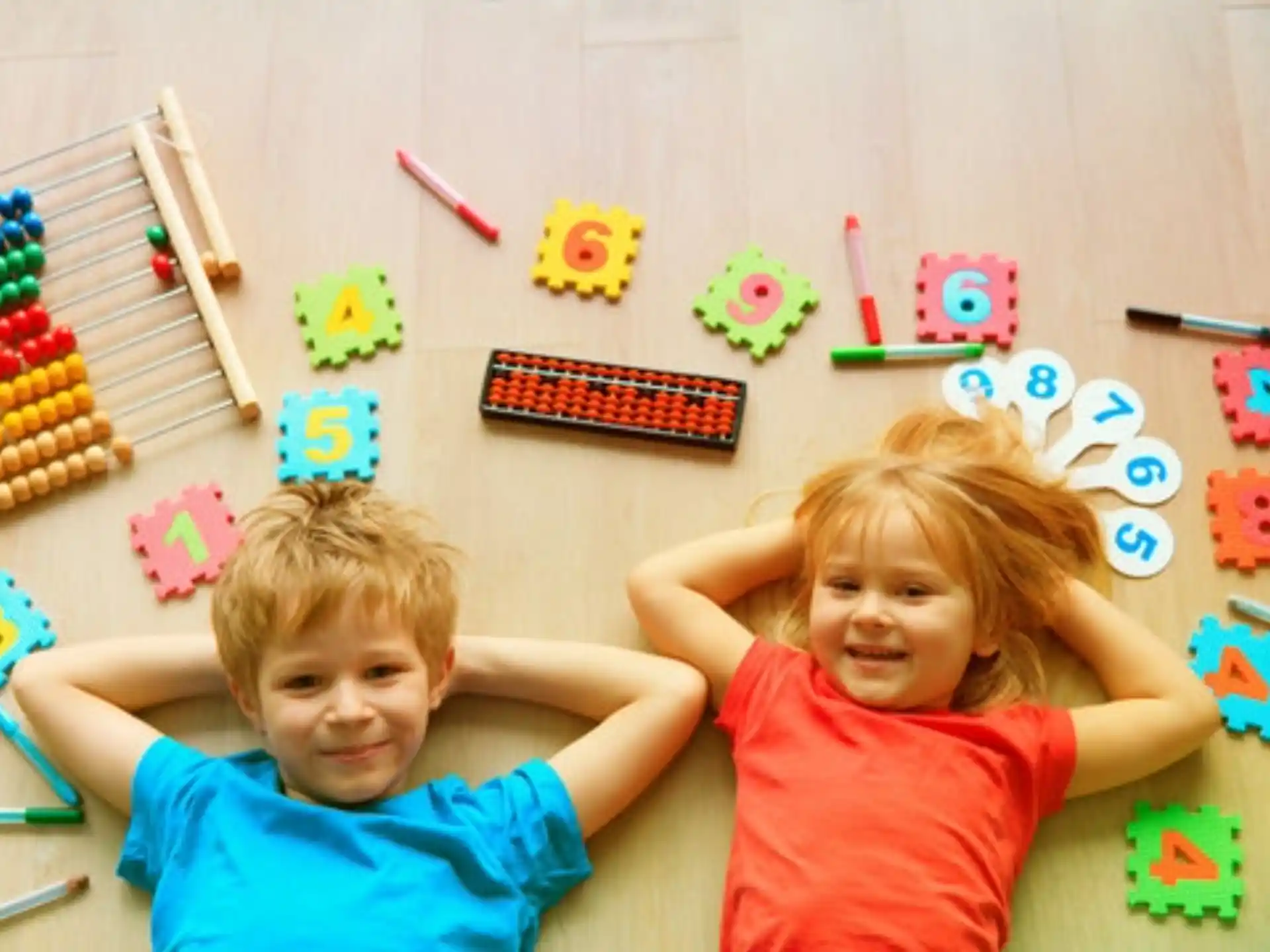 a couple of kids sitting on the floor with toys and a bird cage