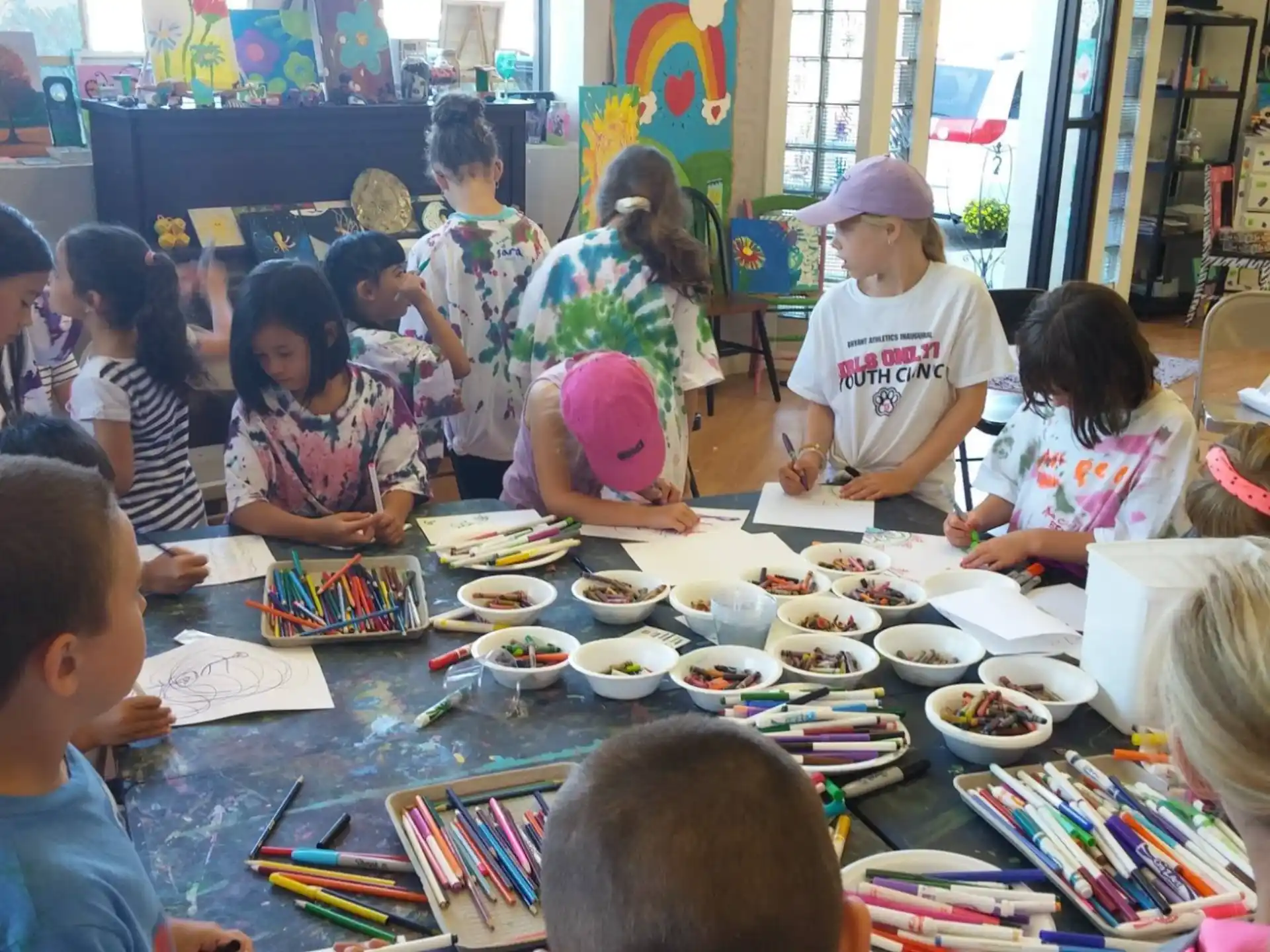 a group of children sitting around a table with food and books