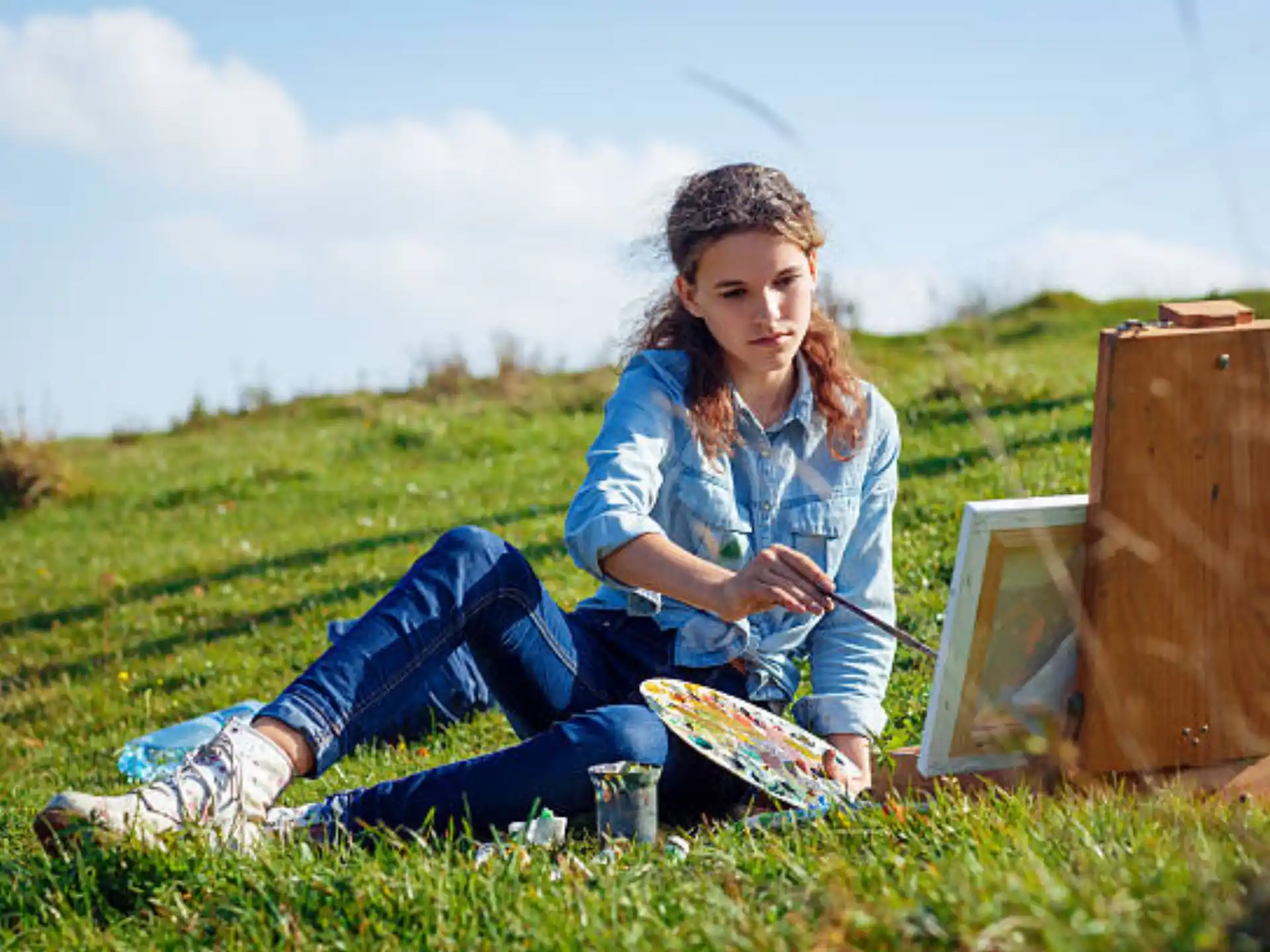 a person sitting on grass next to a laptop