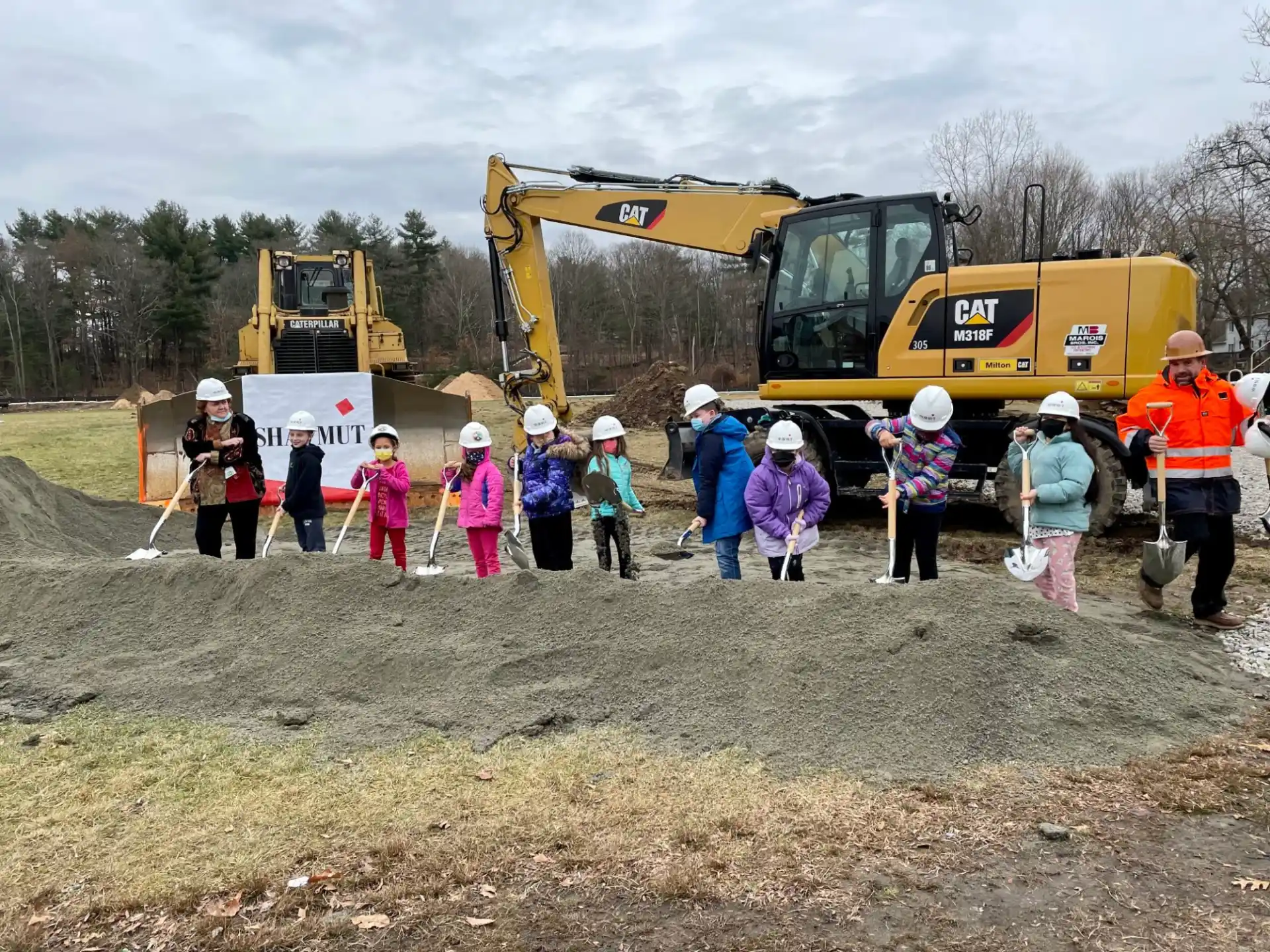 a group of people standing in front of a construction vehicle