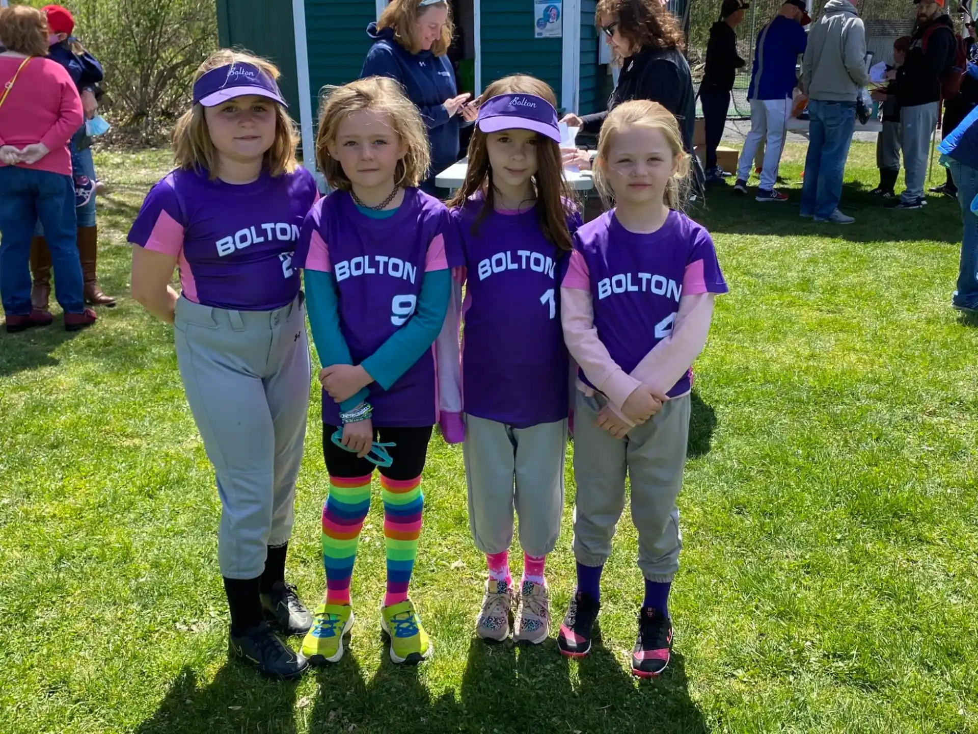 a group of girls in matching purple shirts standing on grass