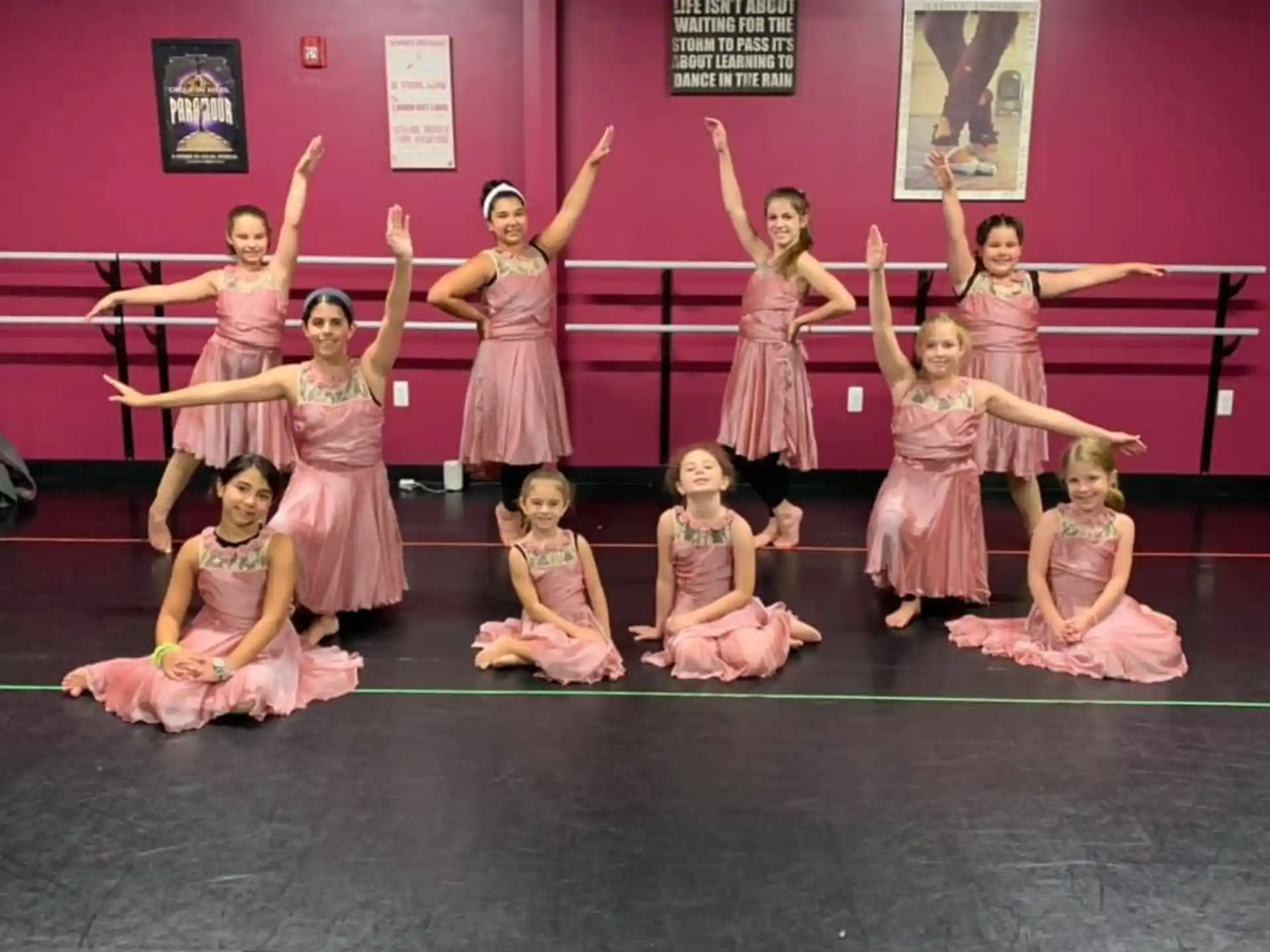 a group of girls in dresses and skirts posing for a photo