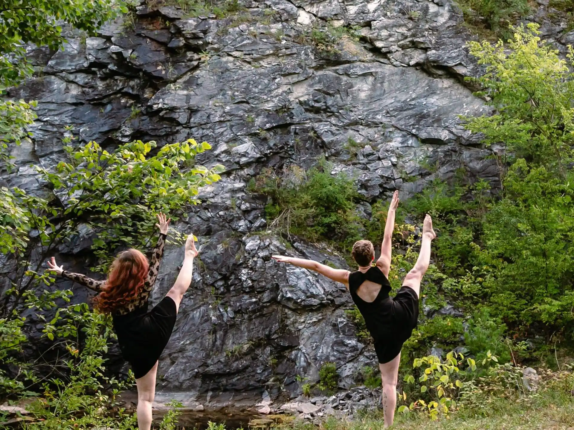 a man and woman jumping in front of a rock cliff