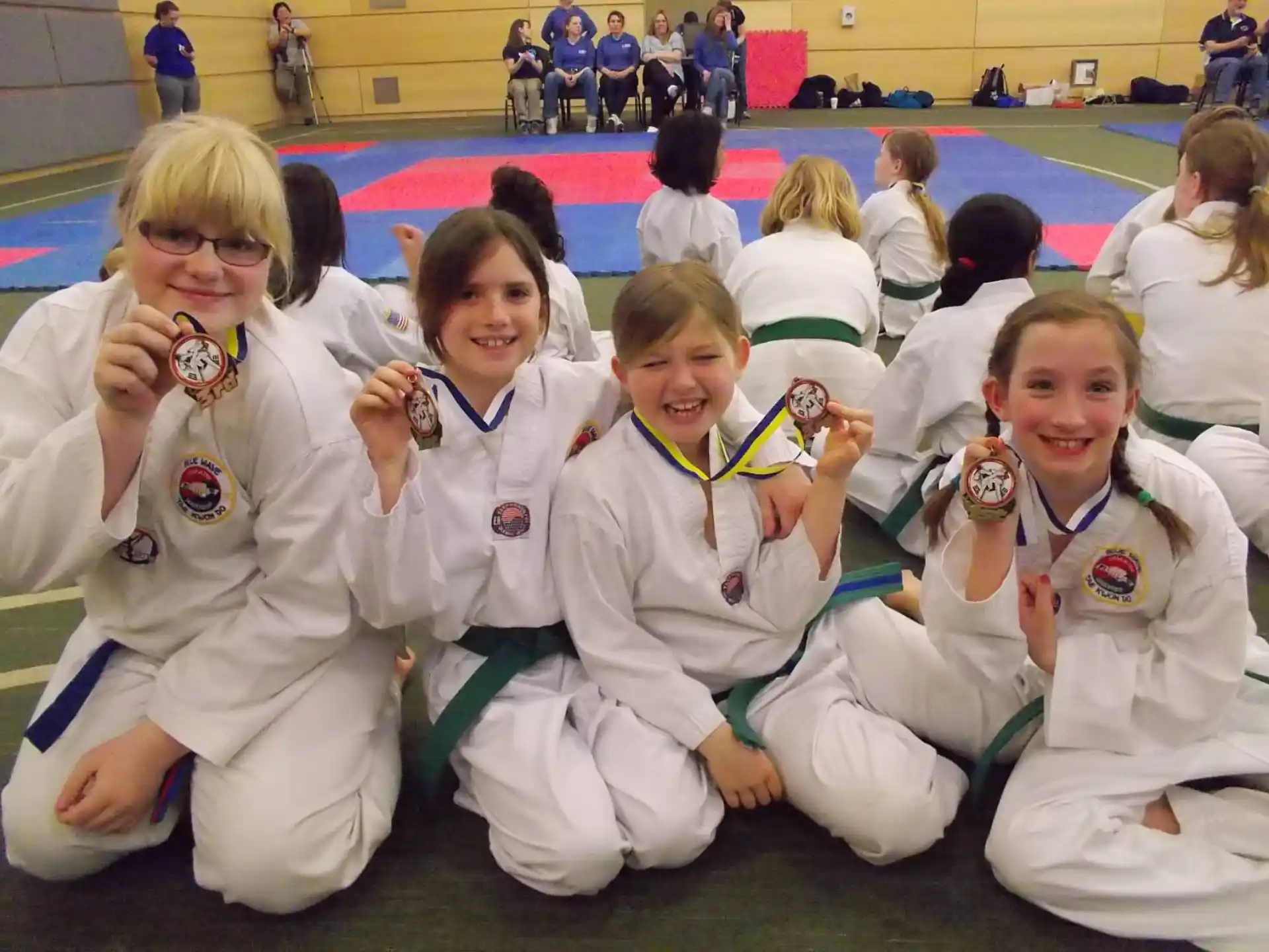 a group of girls in white karate uniforms sitting on the floor