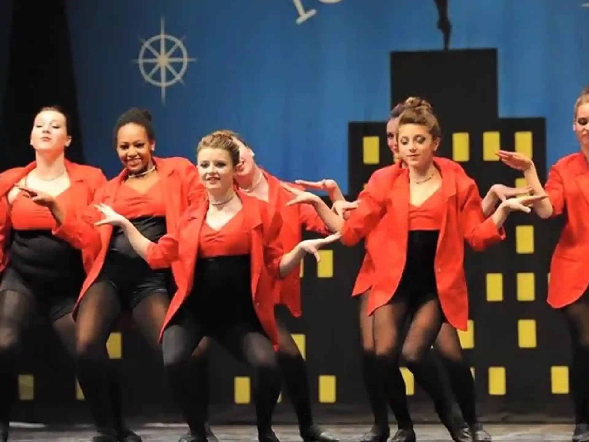 a group of people in red and black outfits dancing on a stage