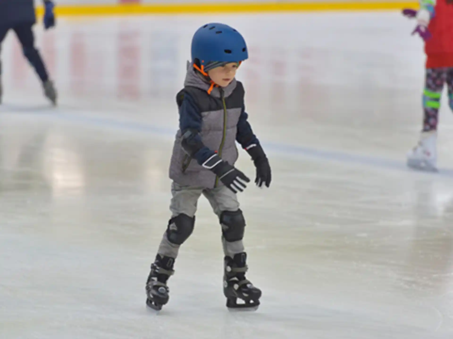 a young boy wearing a helmet and ice skates