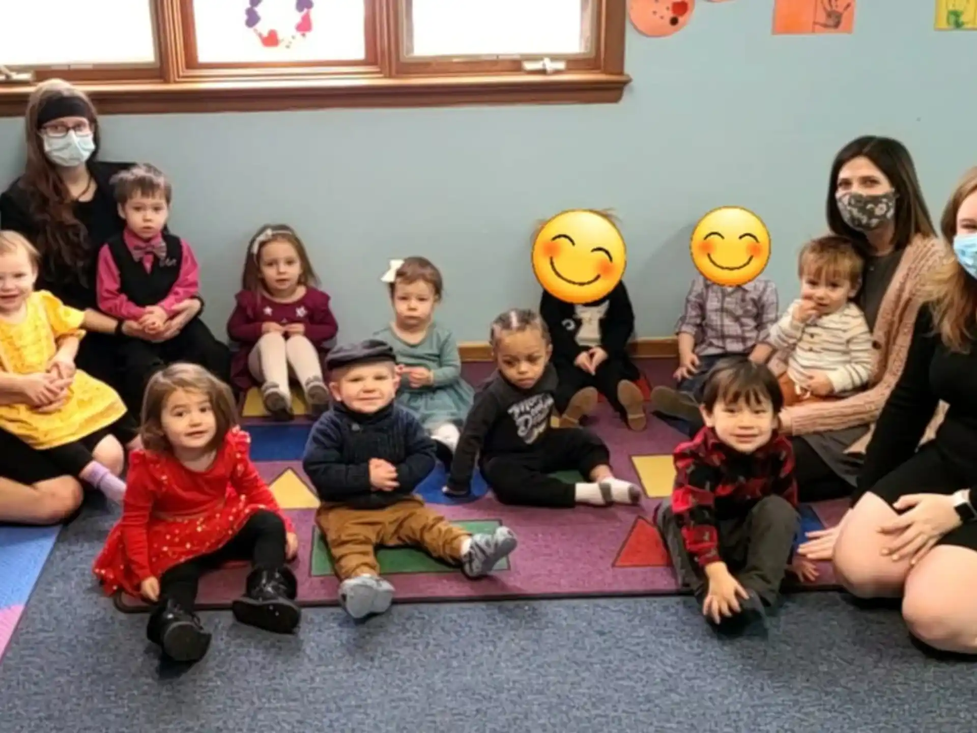 a group of children sitting on the floor with a person in a garment