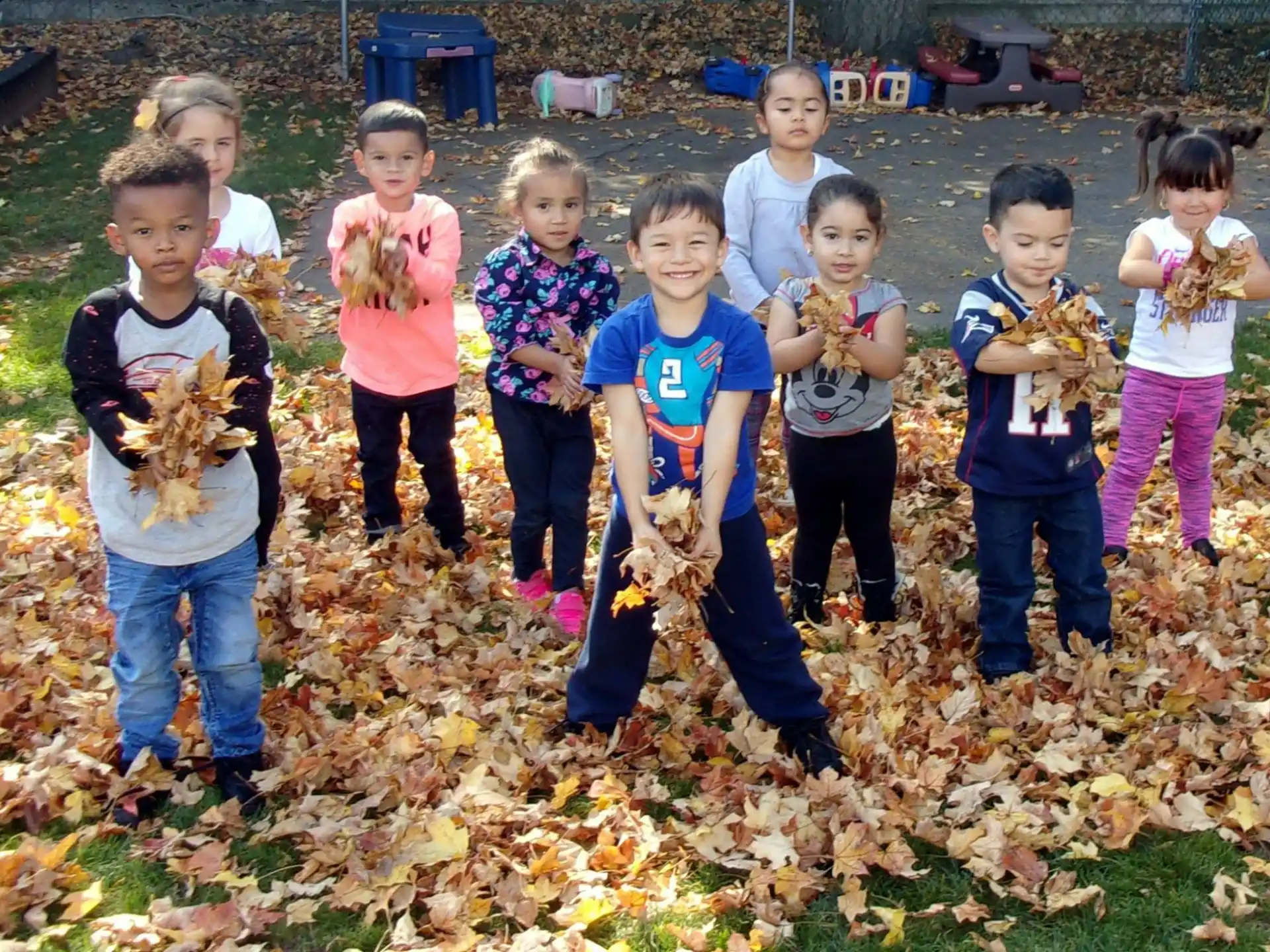 a group of children standing in a pile of leaves