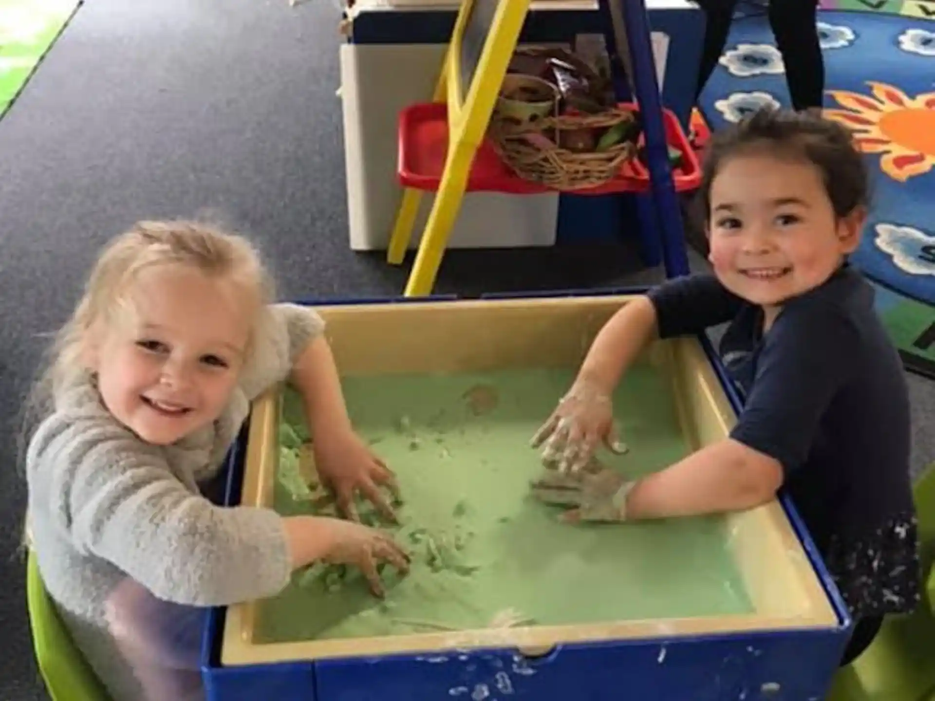 a couple of children playing on a green table