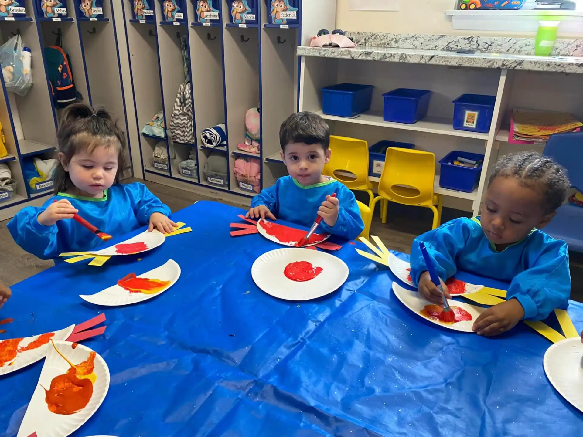a group of kids sitting at a table with food and plates