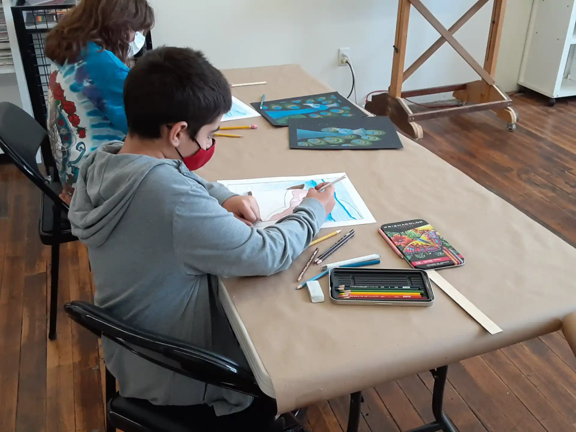 a boy sitting at a table writing on a book