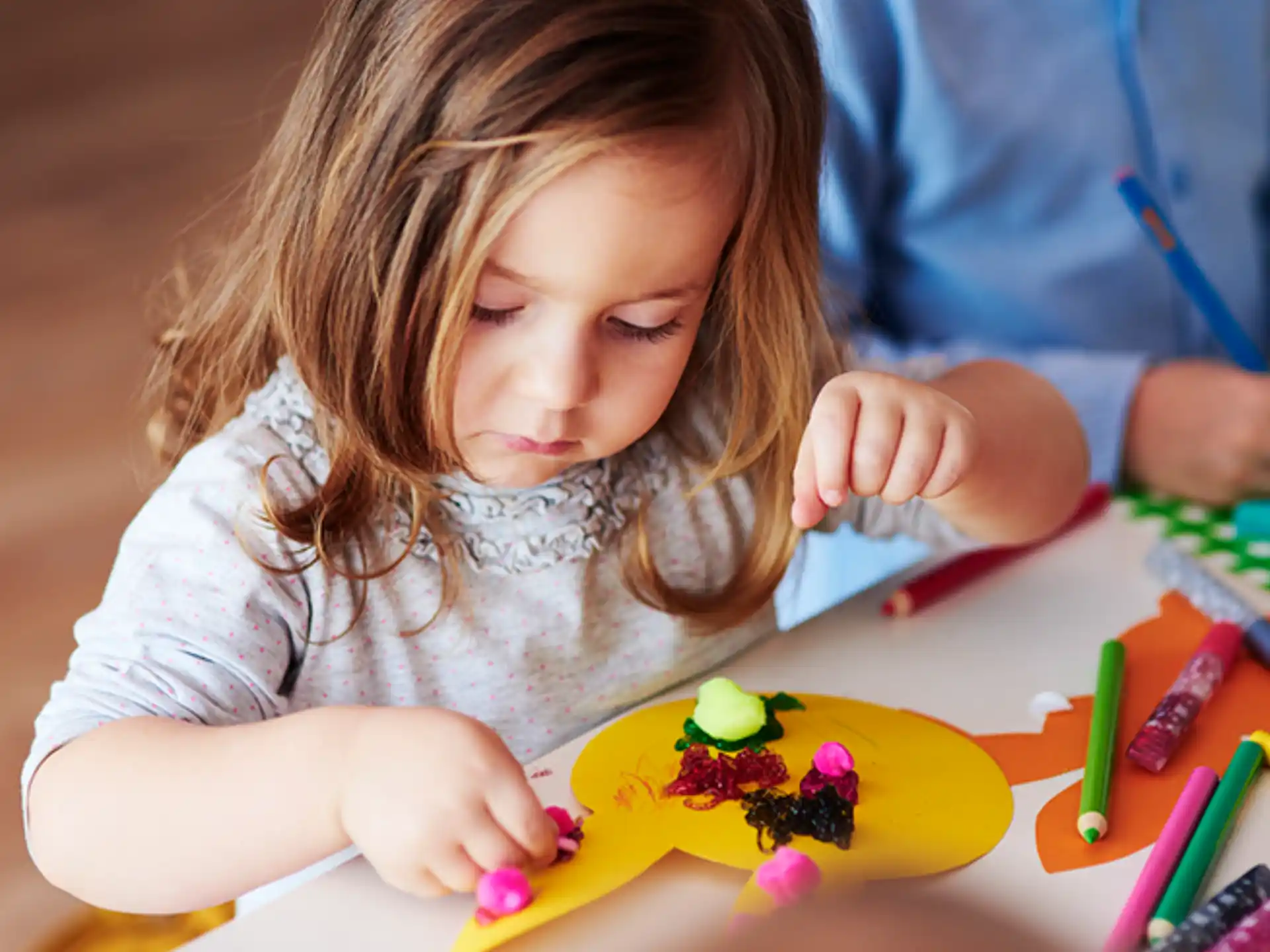 a young girl coloring on a yellow paper