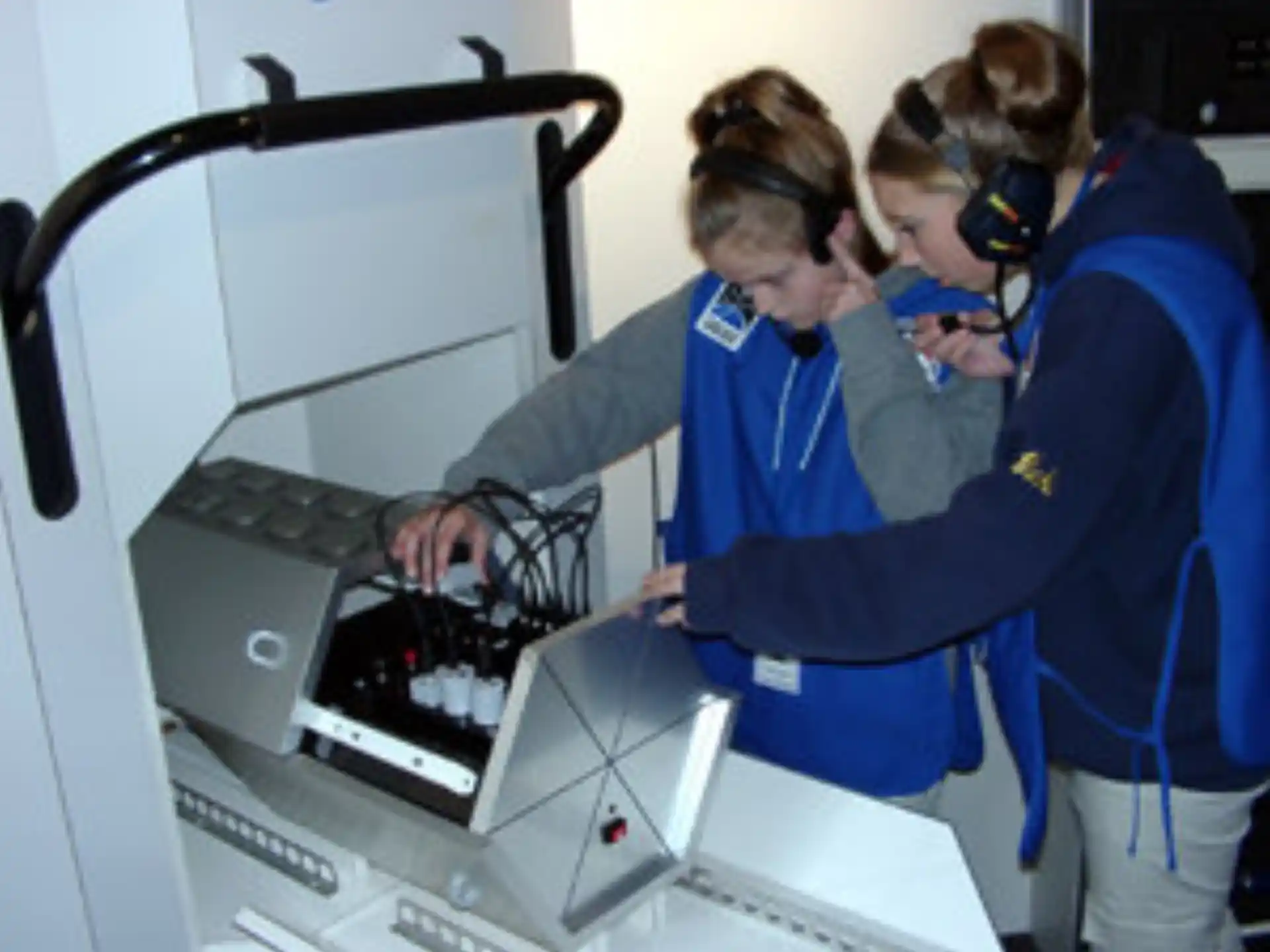 a few people wearing blue jackets working on a computer