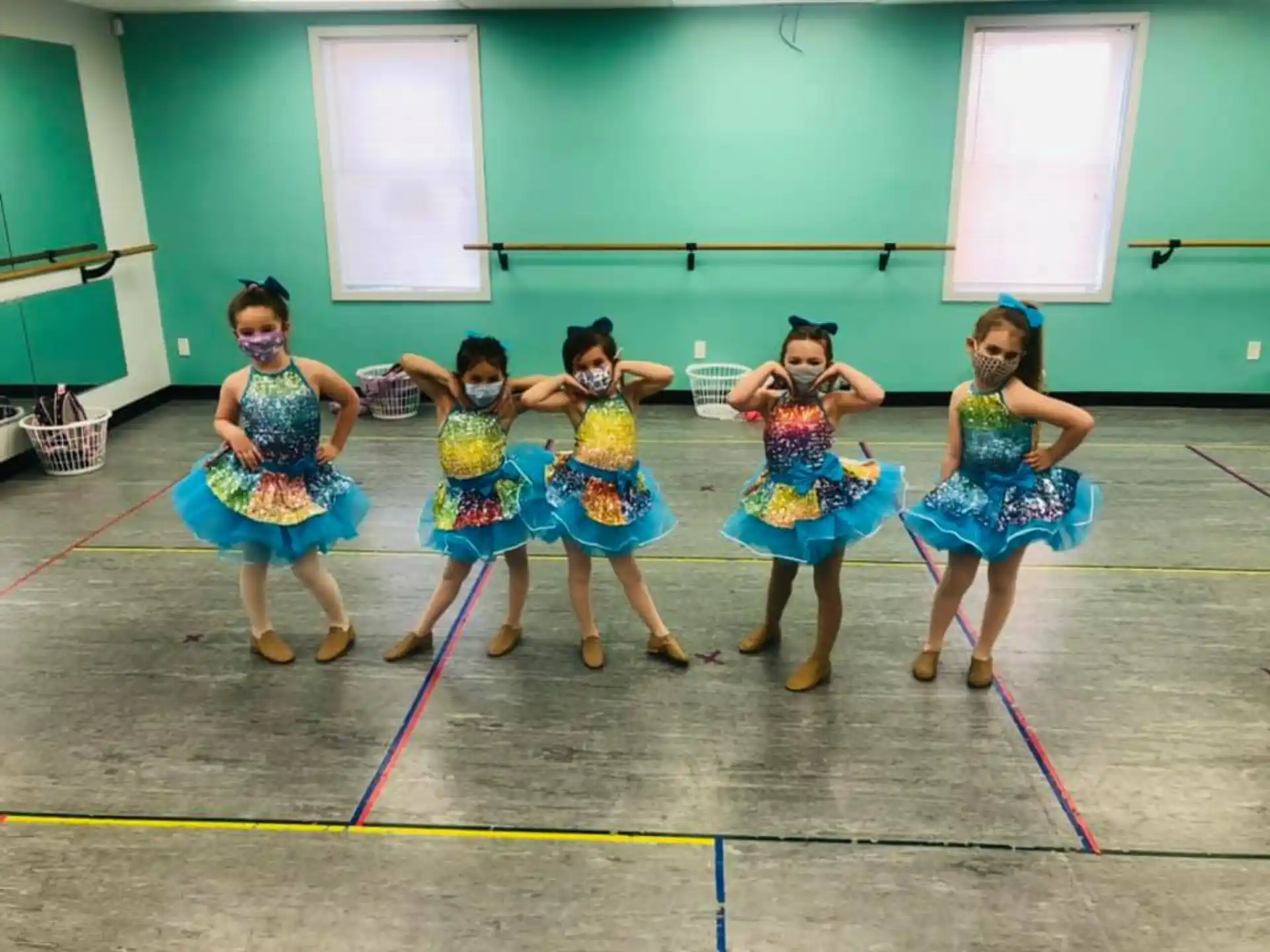 a group of girls in blue dresses dancing on a basketball court