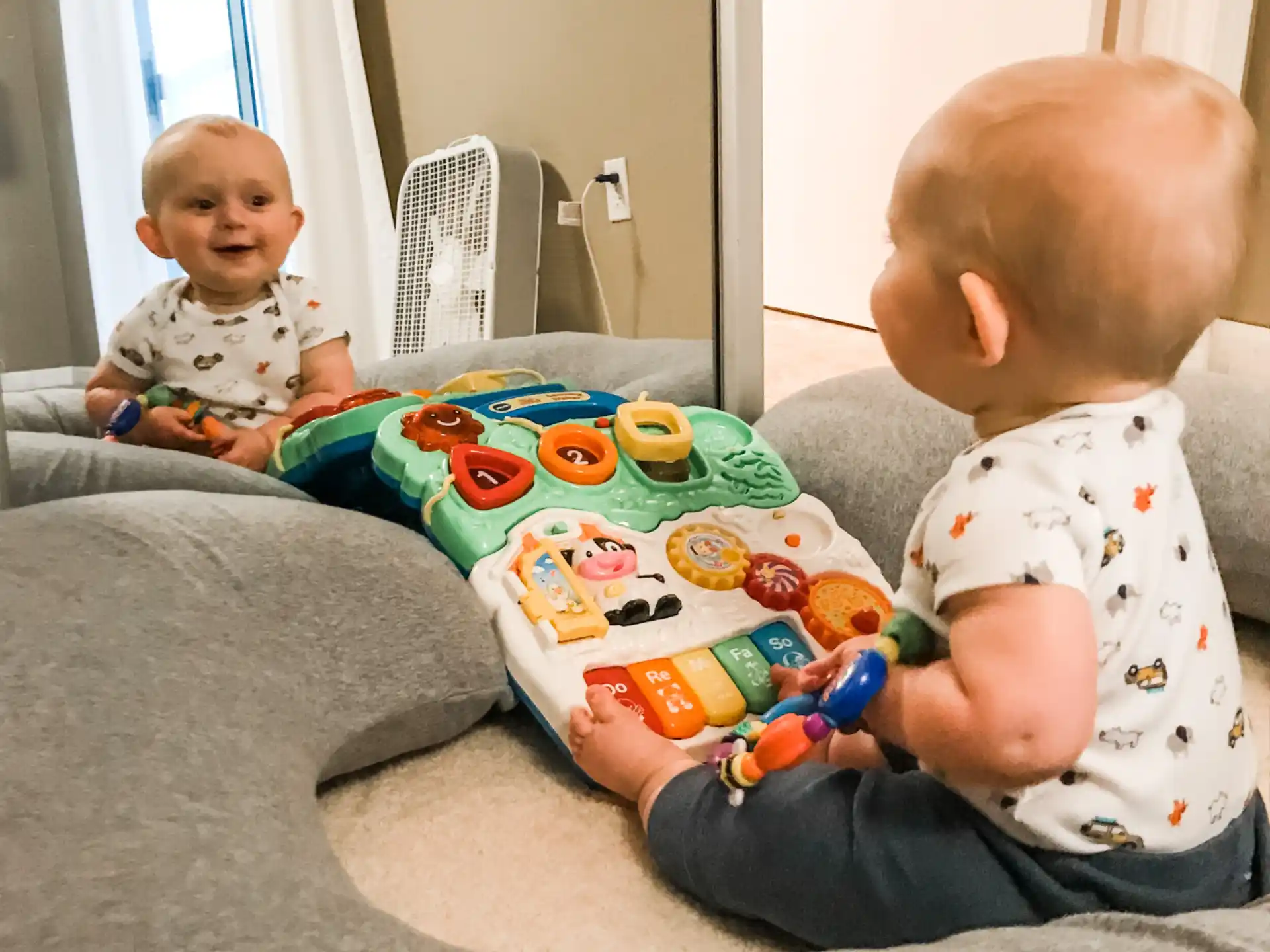 a baby sitting on the floor with a toy in front of it