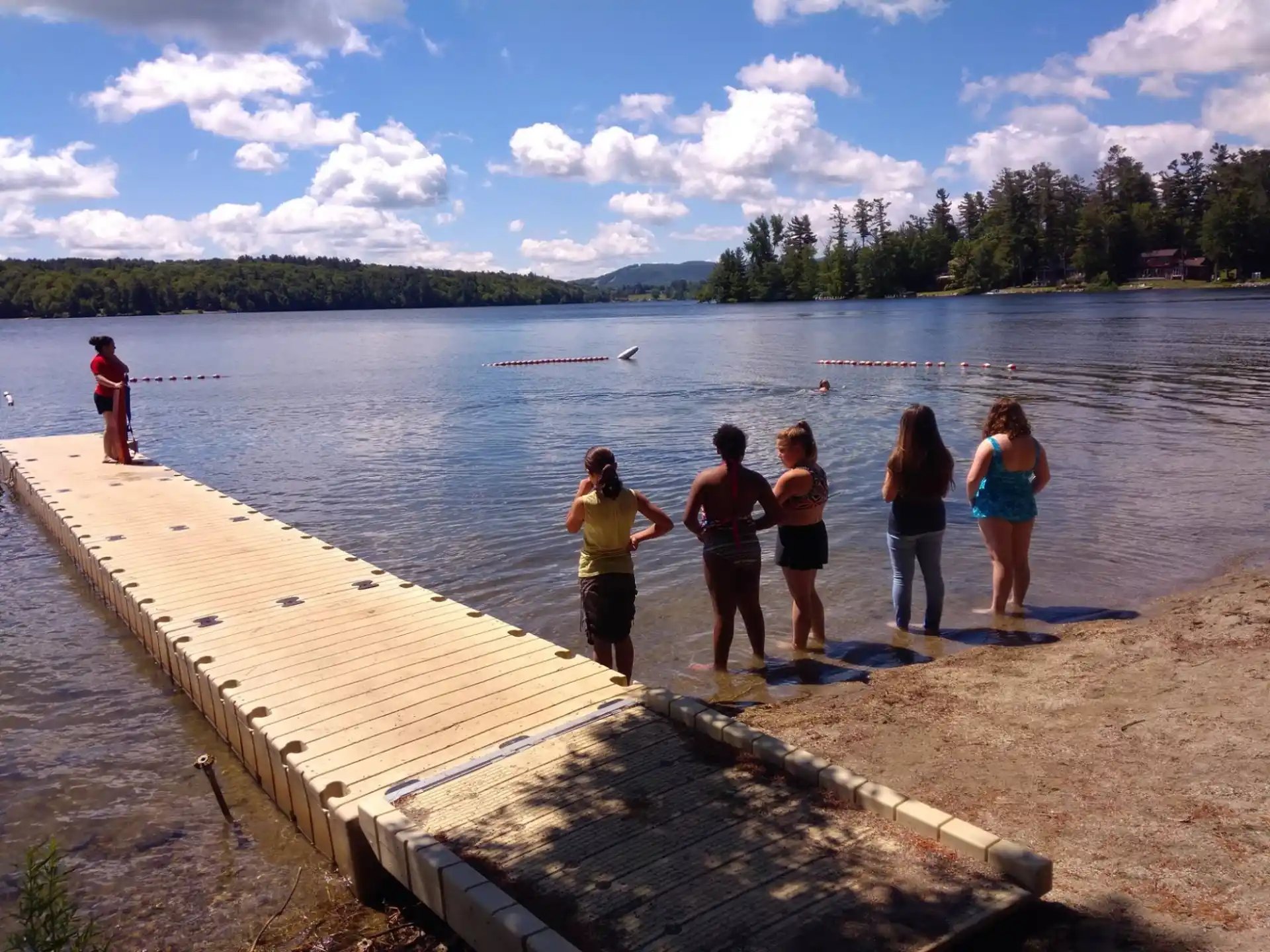 a group of people standing on a dock by a body of water