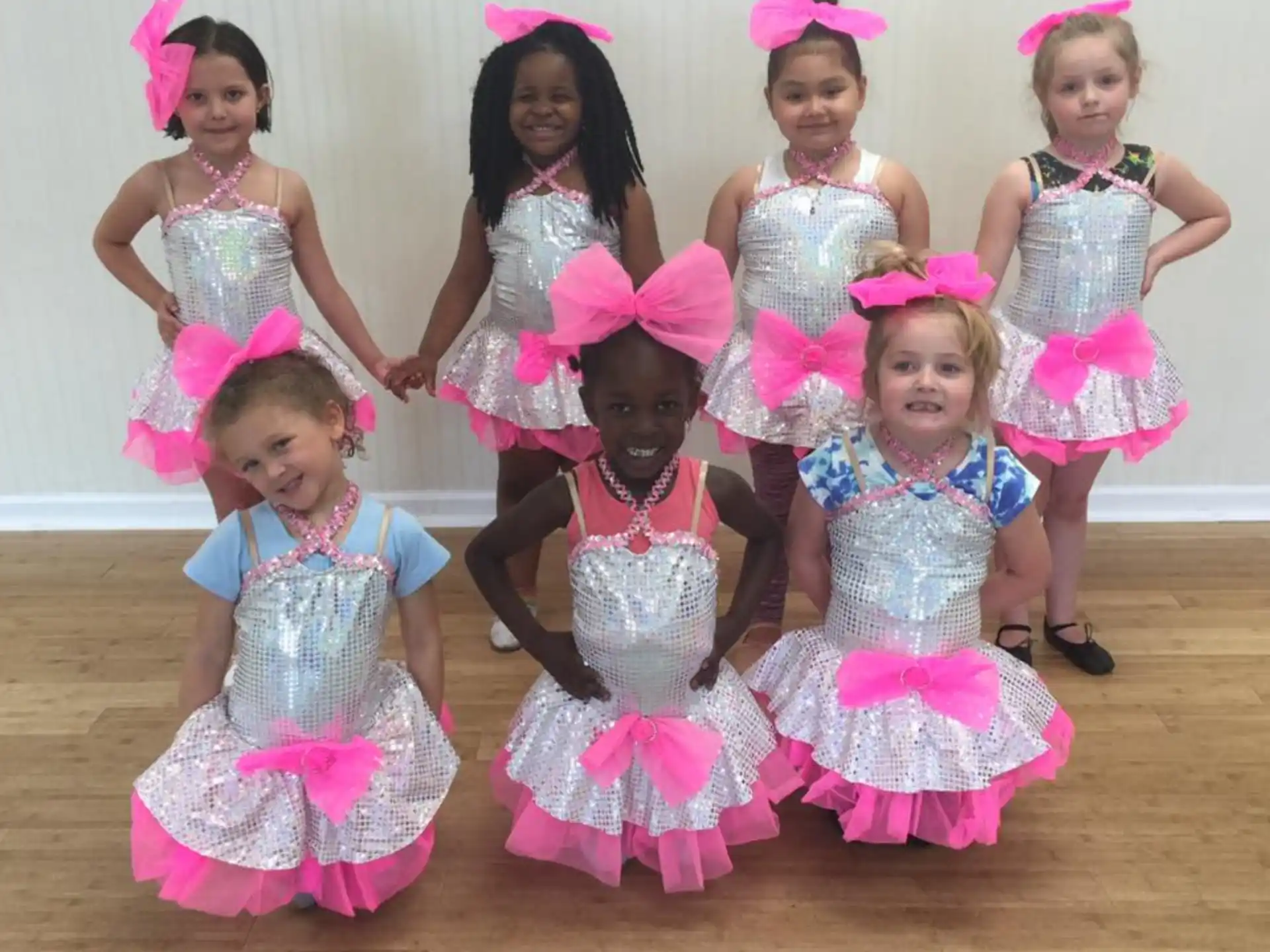 a group of girls wearing pink and white dresses and posing for a photo