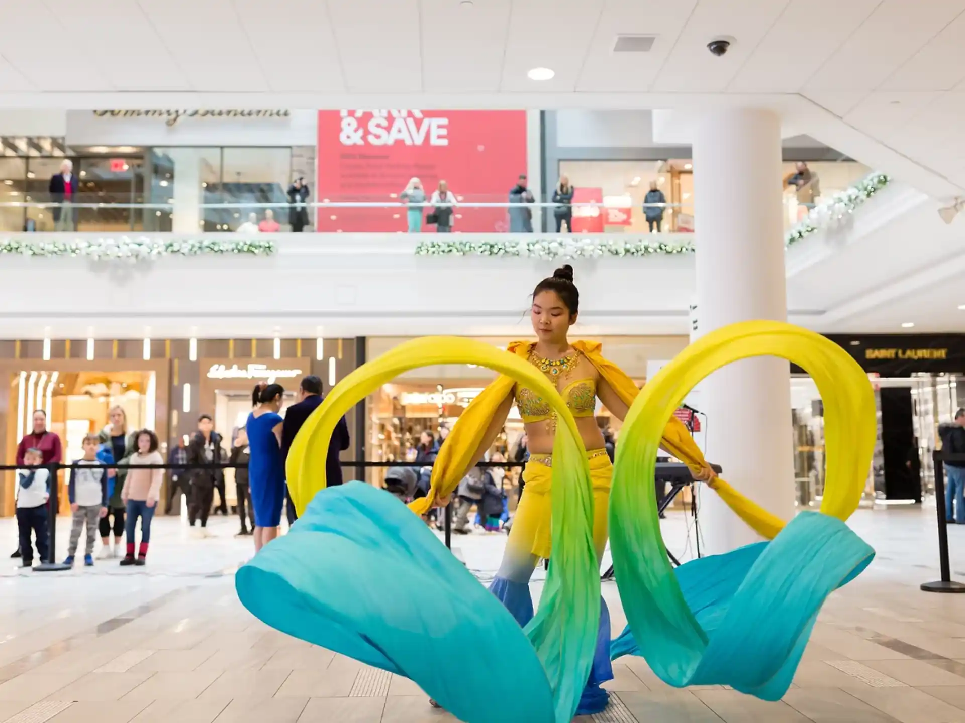 a person standing behind a large yellow and blue sculpture in a mall