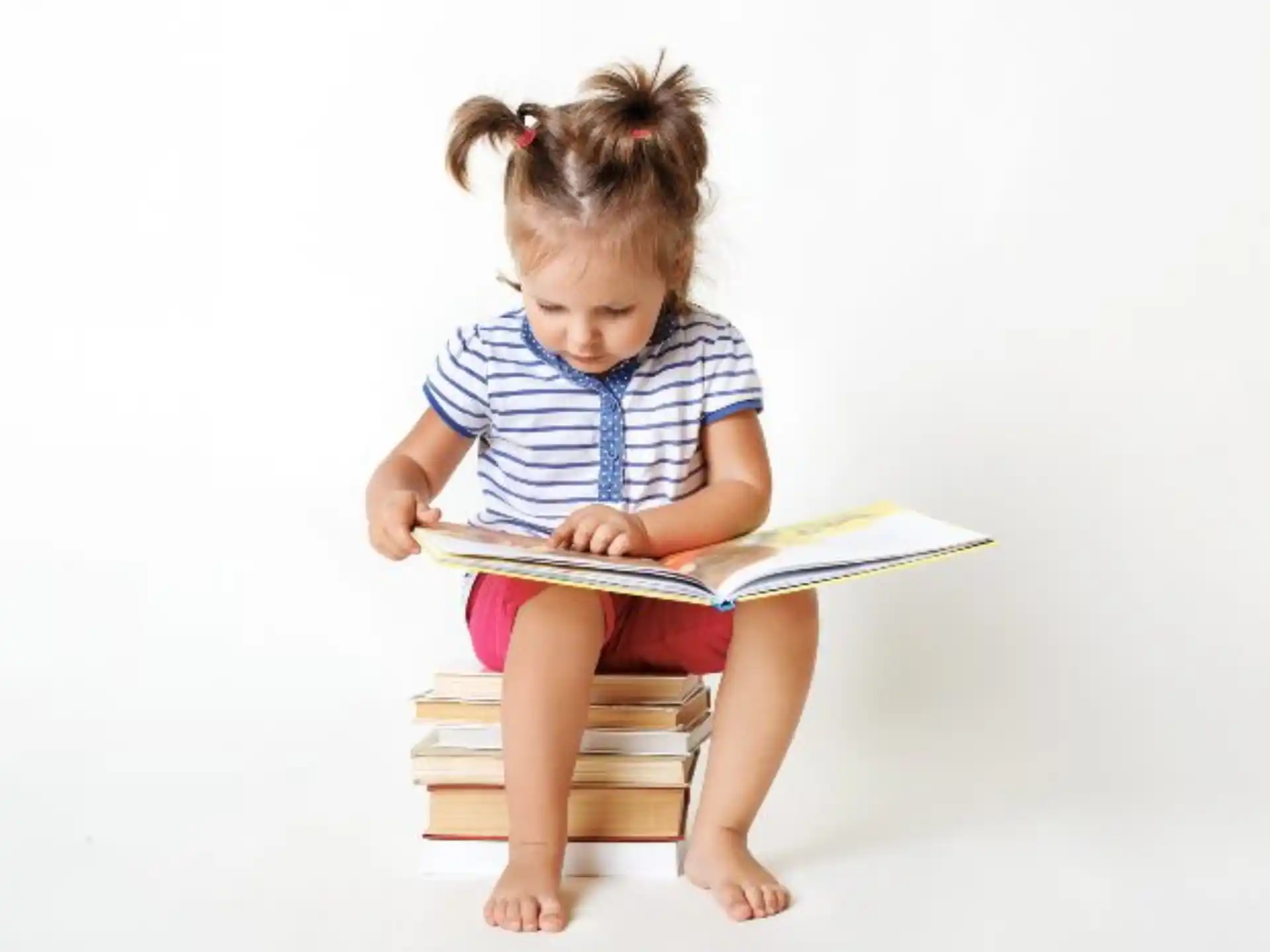 a young girl sitting on a chair reading a book