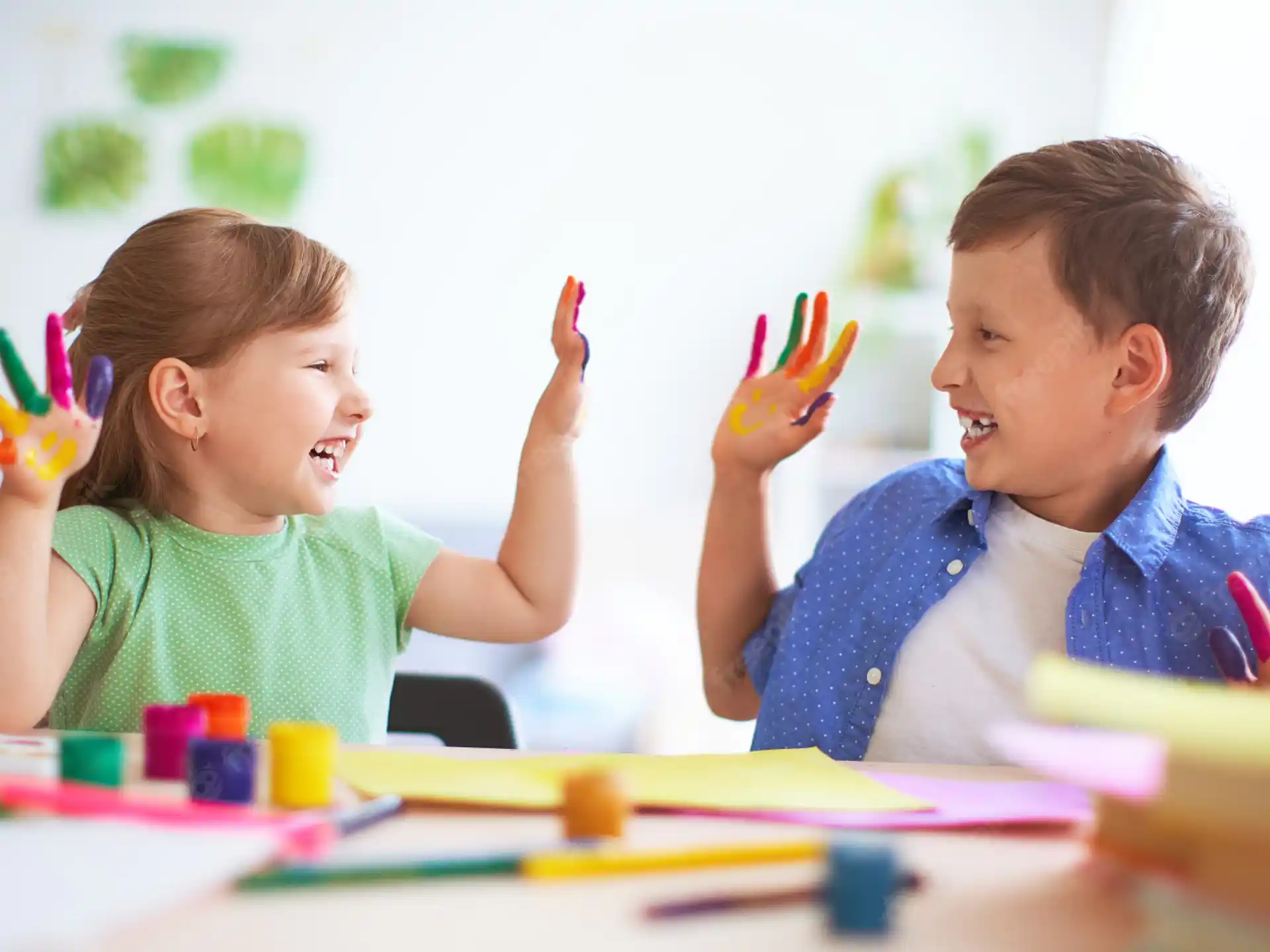 a boy and girl sitting at a table with colored pencils