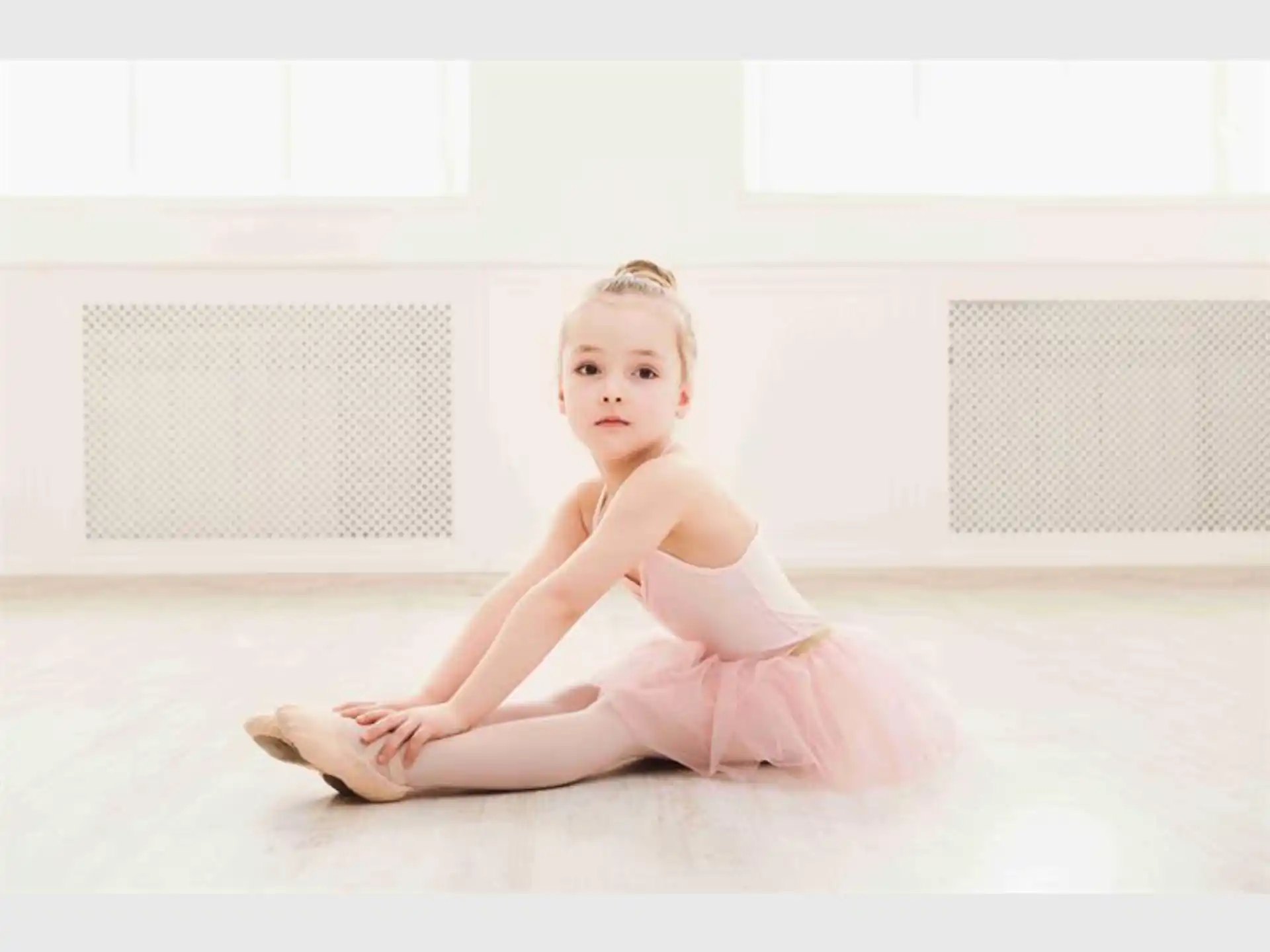 a girl in a tutu sitting on the floor