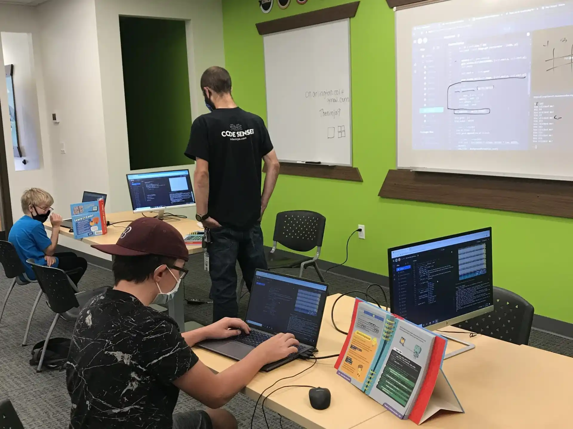 a group of people in a room with computers and a projection screen