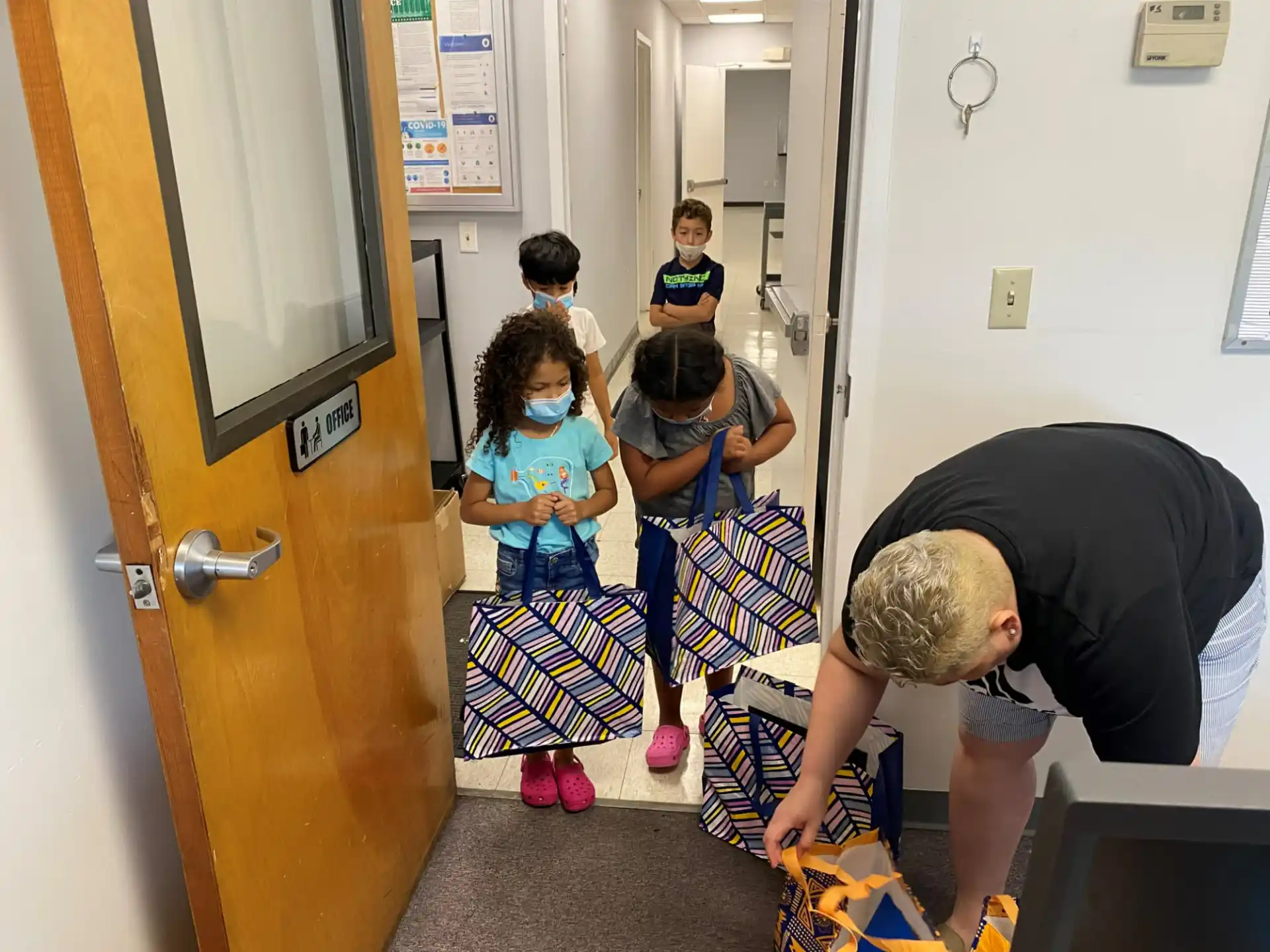 a person and a group of children in a hallway