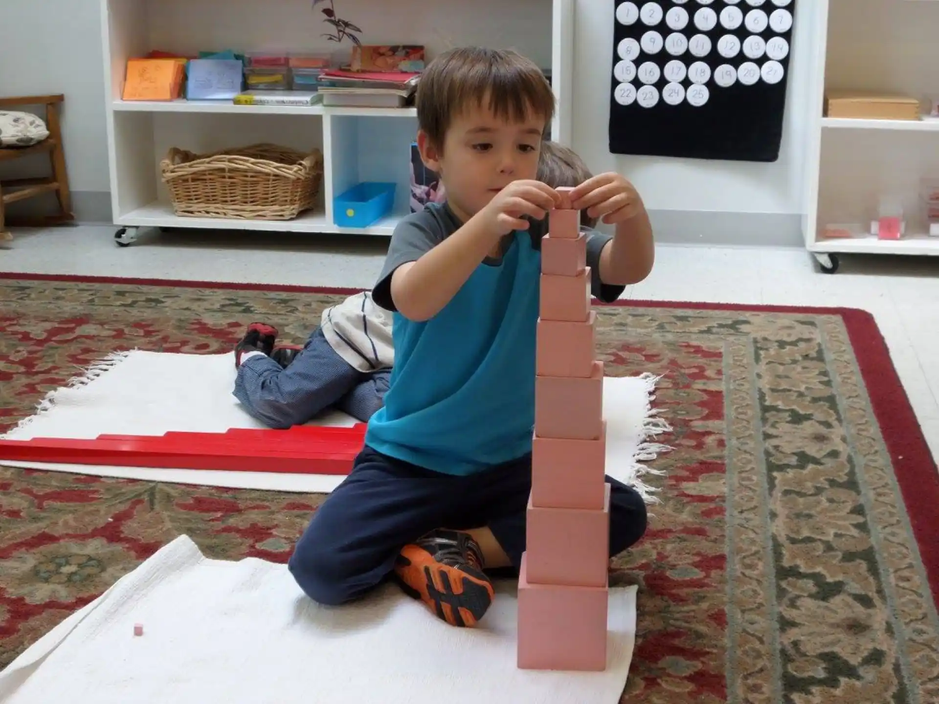 a boy sitting on the floor with a stack of blocks