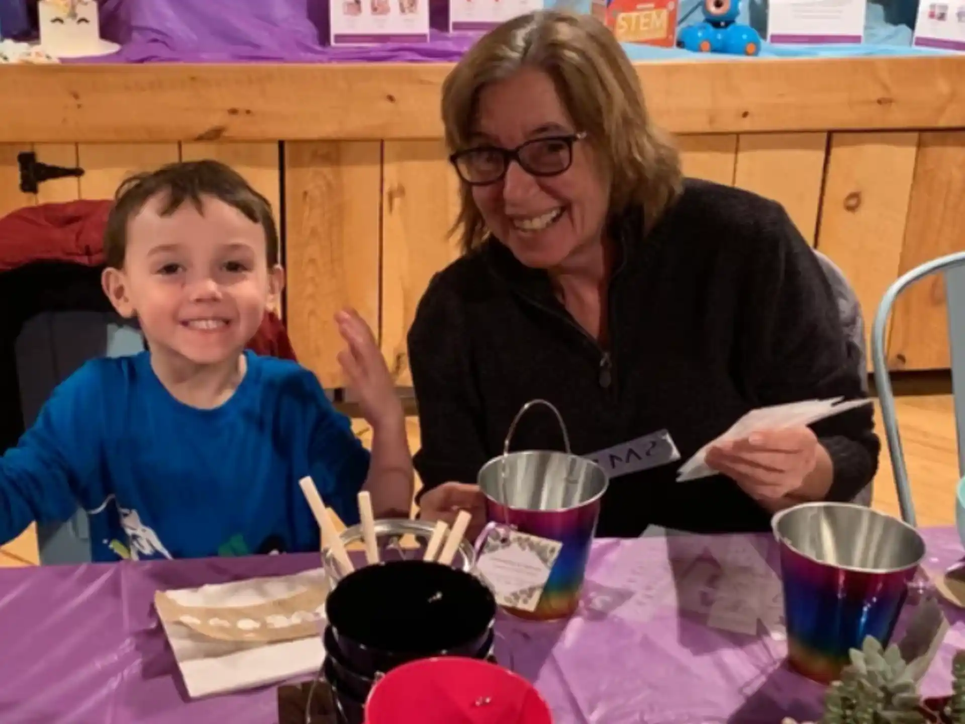 a woman and a boy sitting at a table with food and drinks