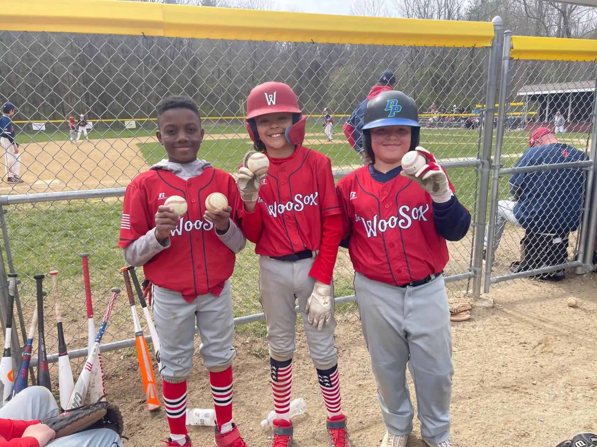 a group of kids in red uniforms holding baseball bats
