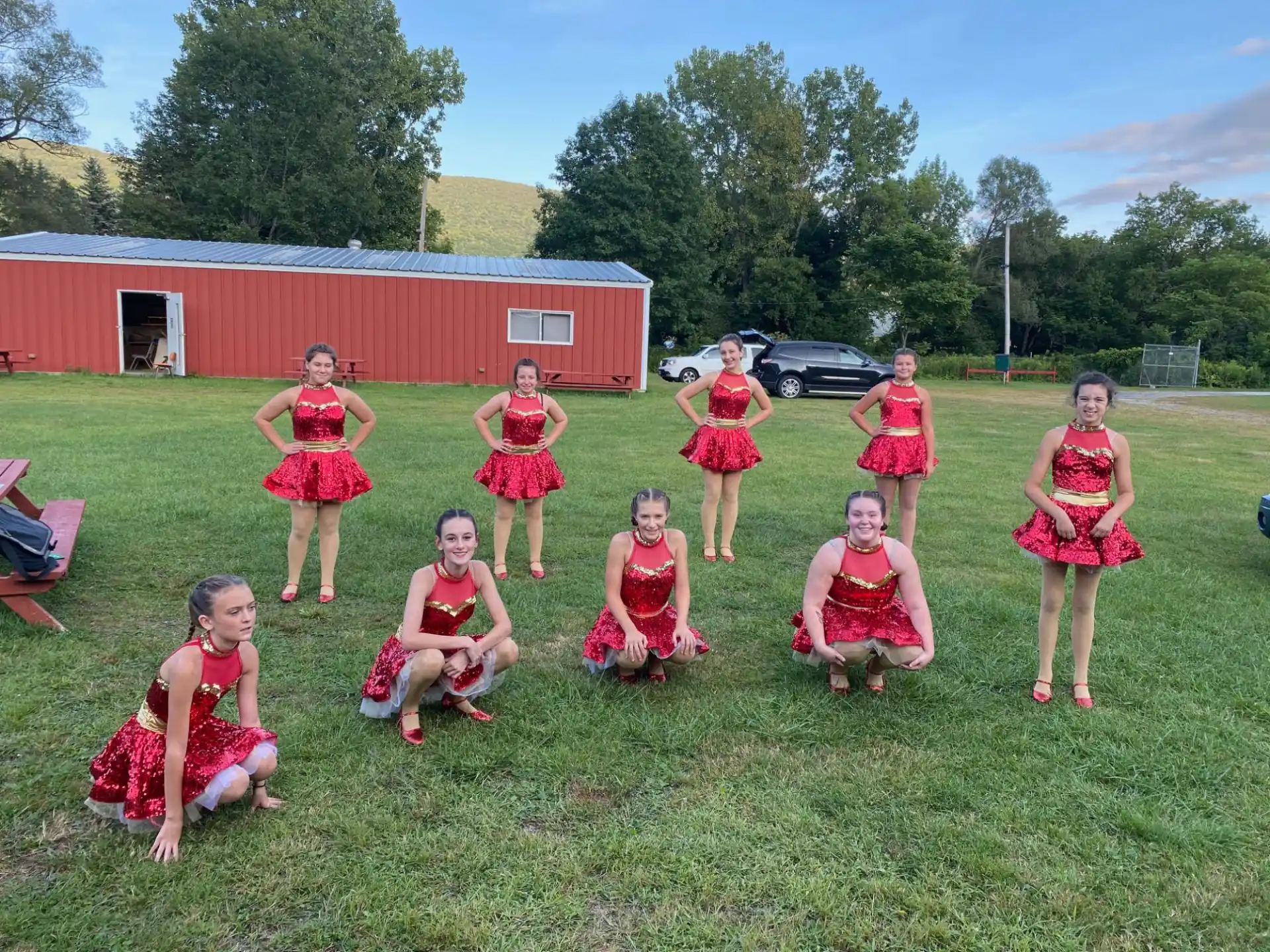 a group of girls in red dresses posing in a grassy field