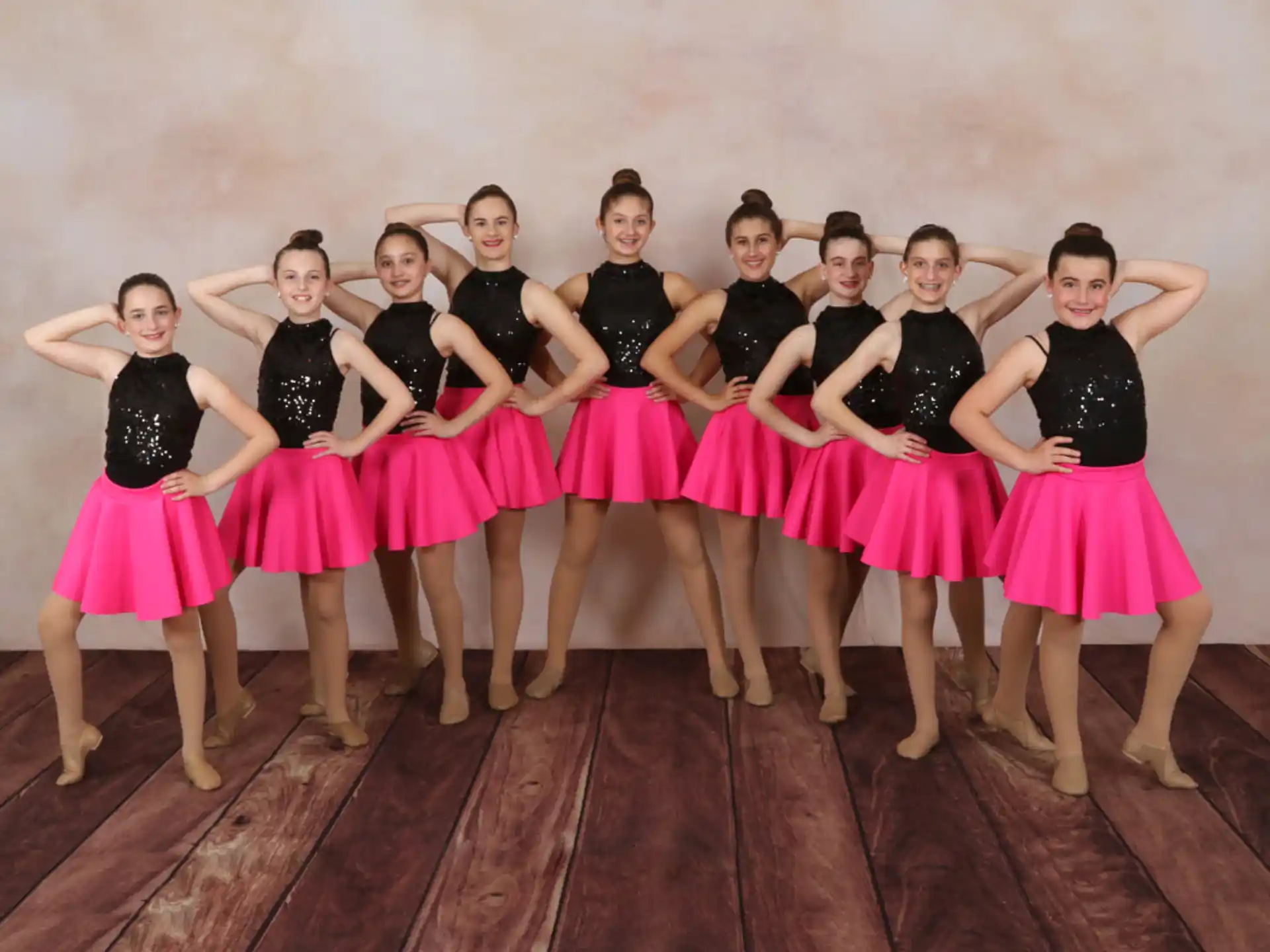 a group of women in black and pink dresses posing for a photo