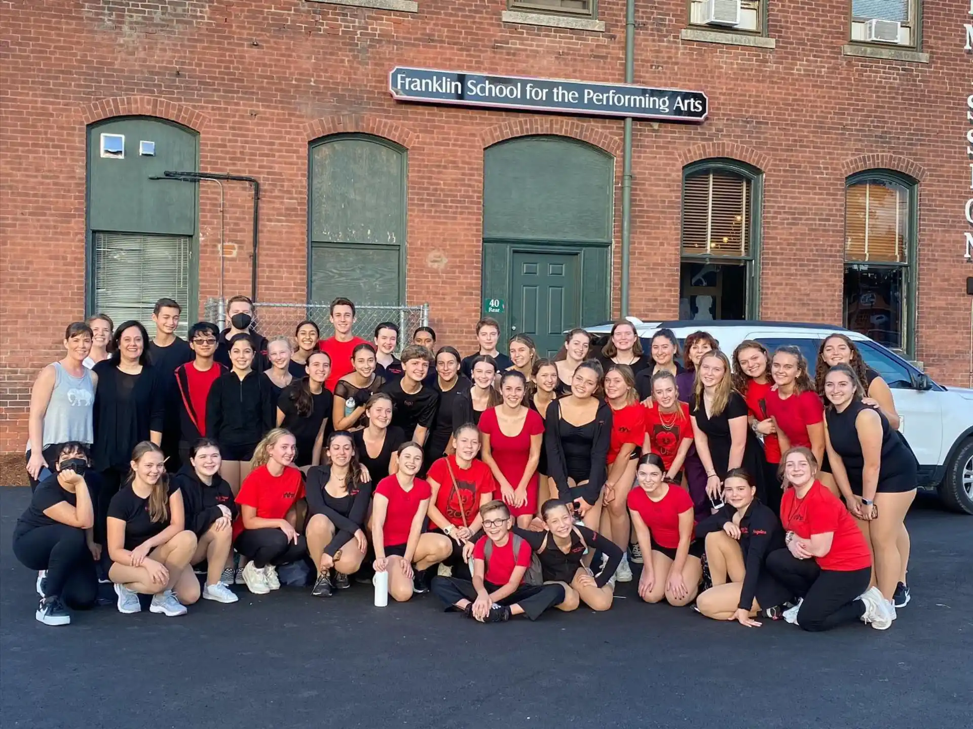 a group of people posing for a photo in front of a brick building