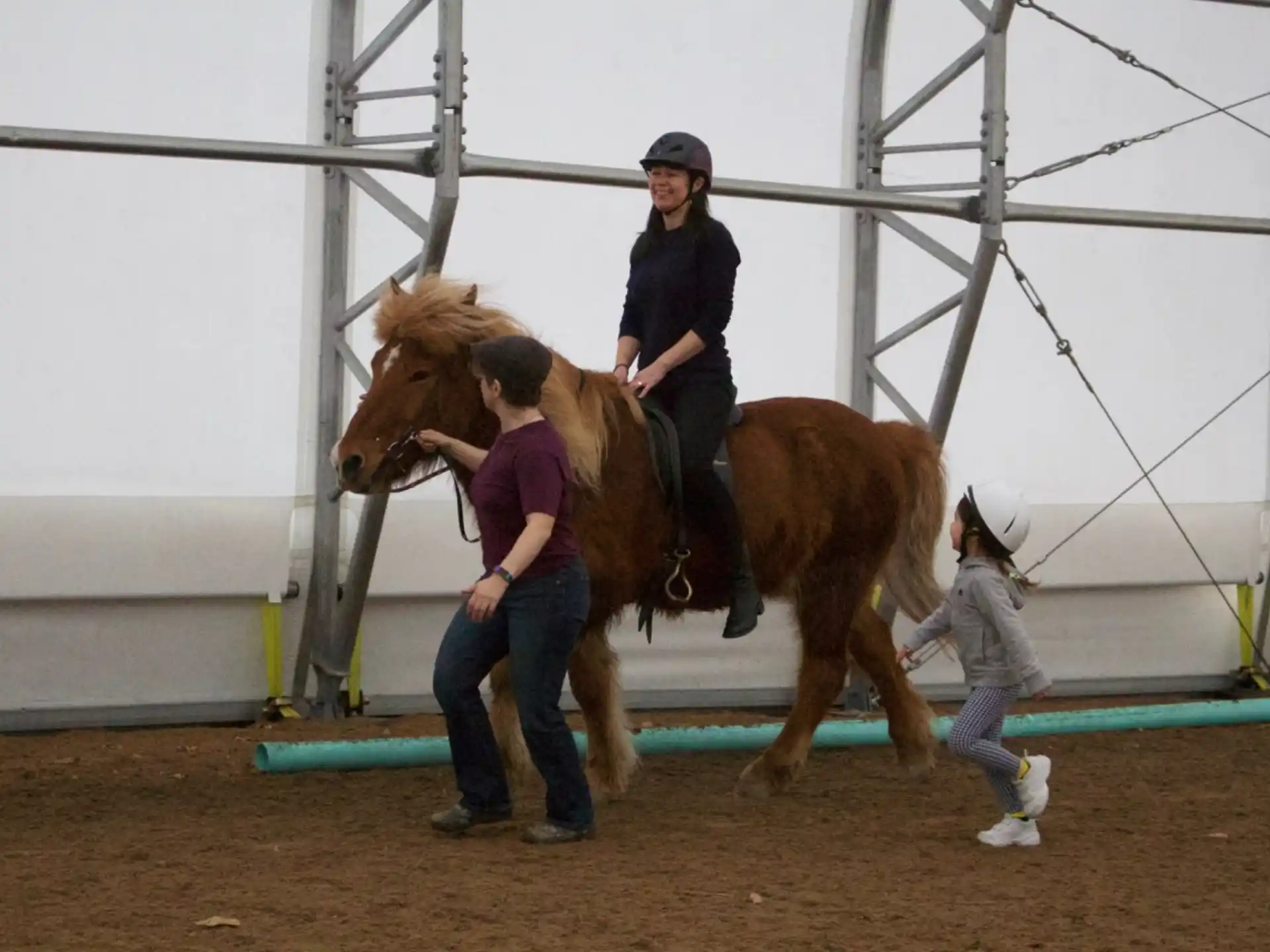 a woman riding a horse with a man standing on the back