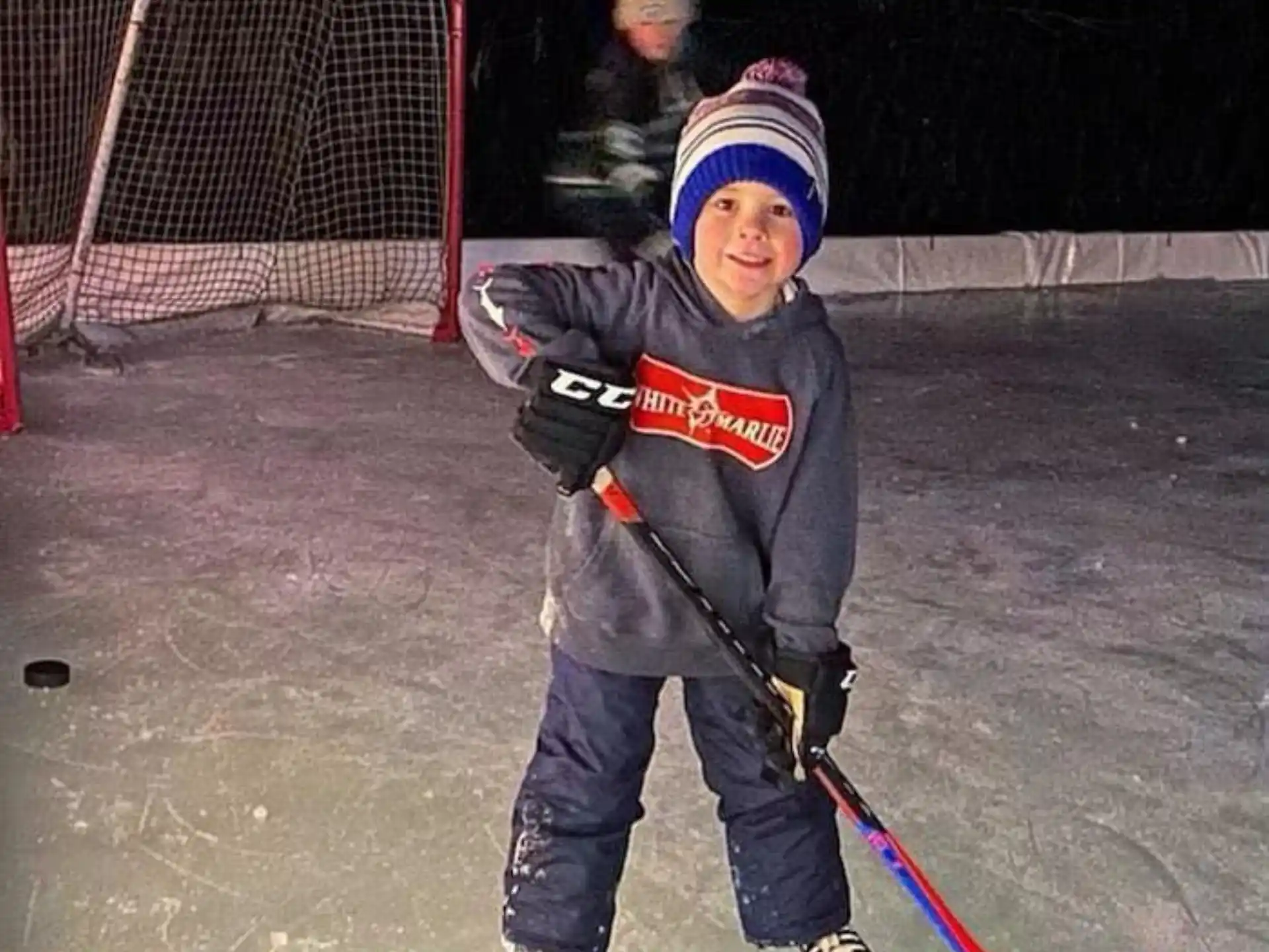 a boy wearing a hockey uniform and holding a hockey stick