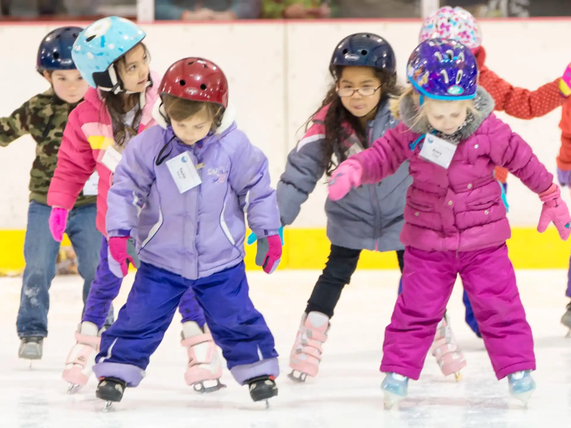 a group of kids wearing helmets and ice skates