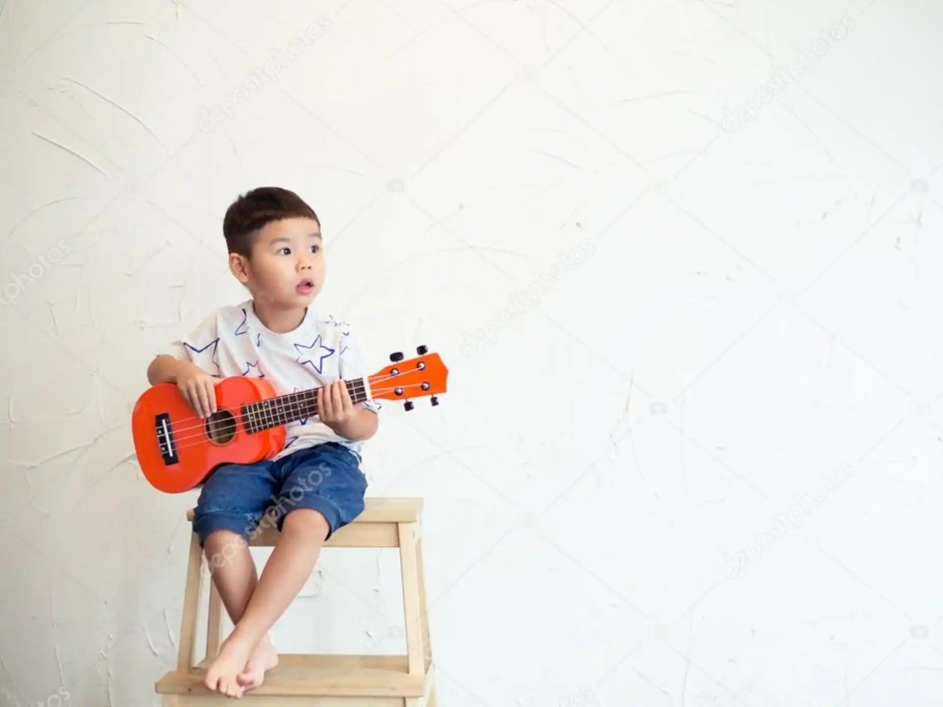a boy sitting on a chair playing a guitar