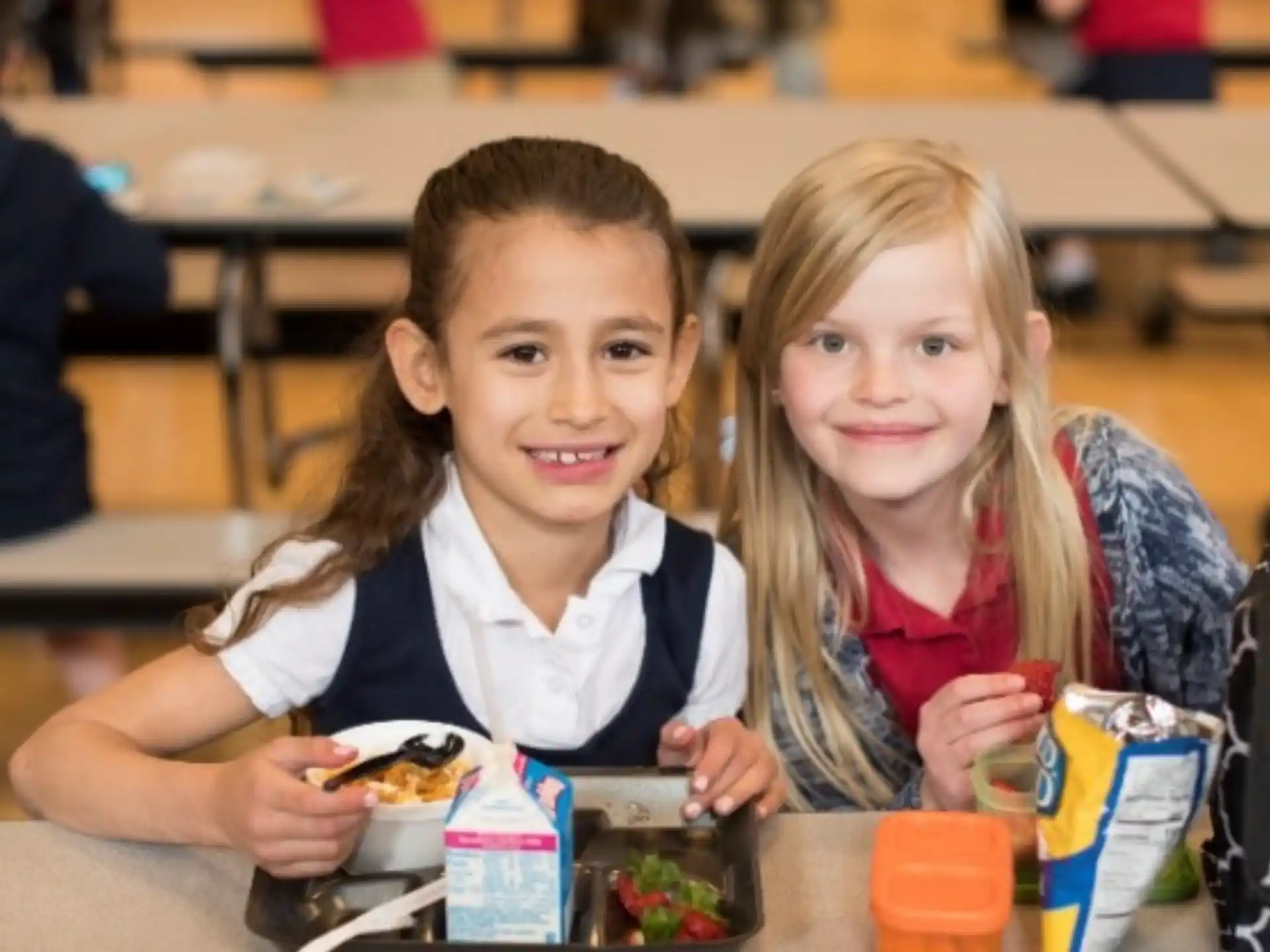 a couple of girls sitting at a table eating food