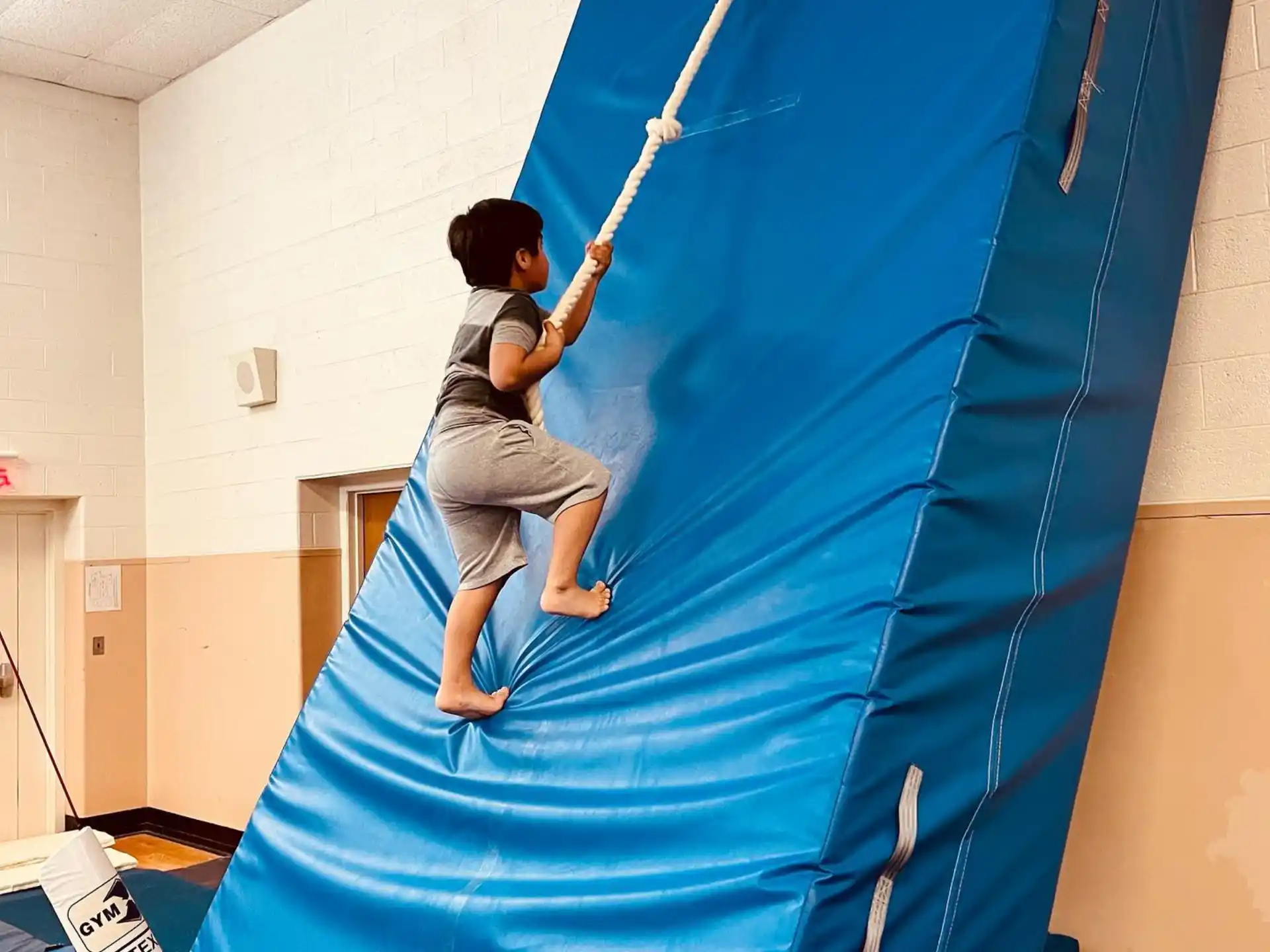 a boy climbing a blue tent