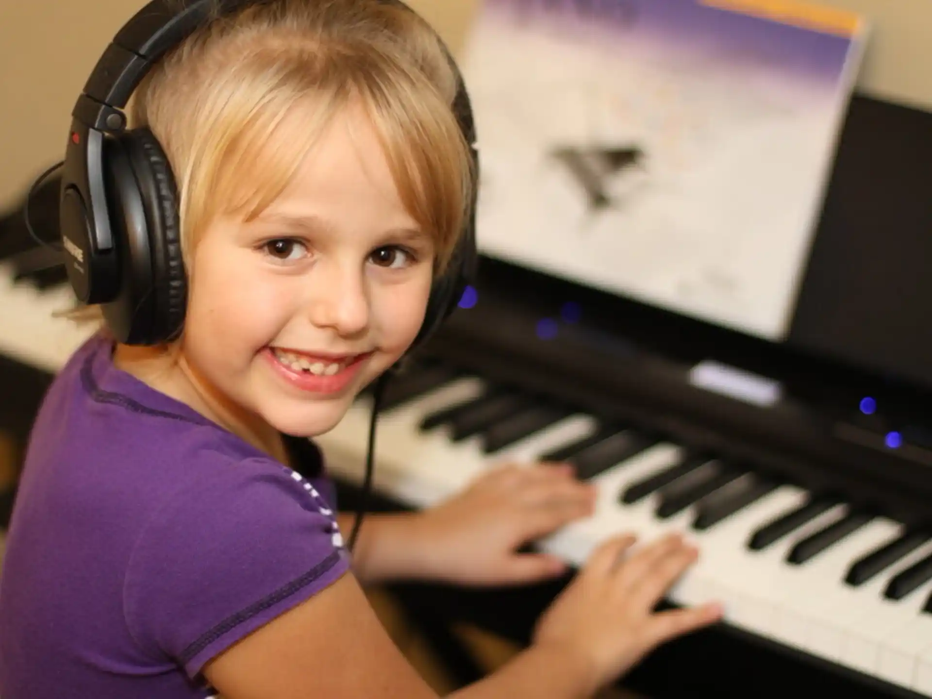 a girl wearing headphones and playing a piano