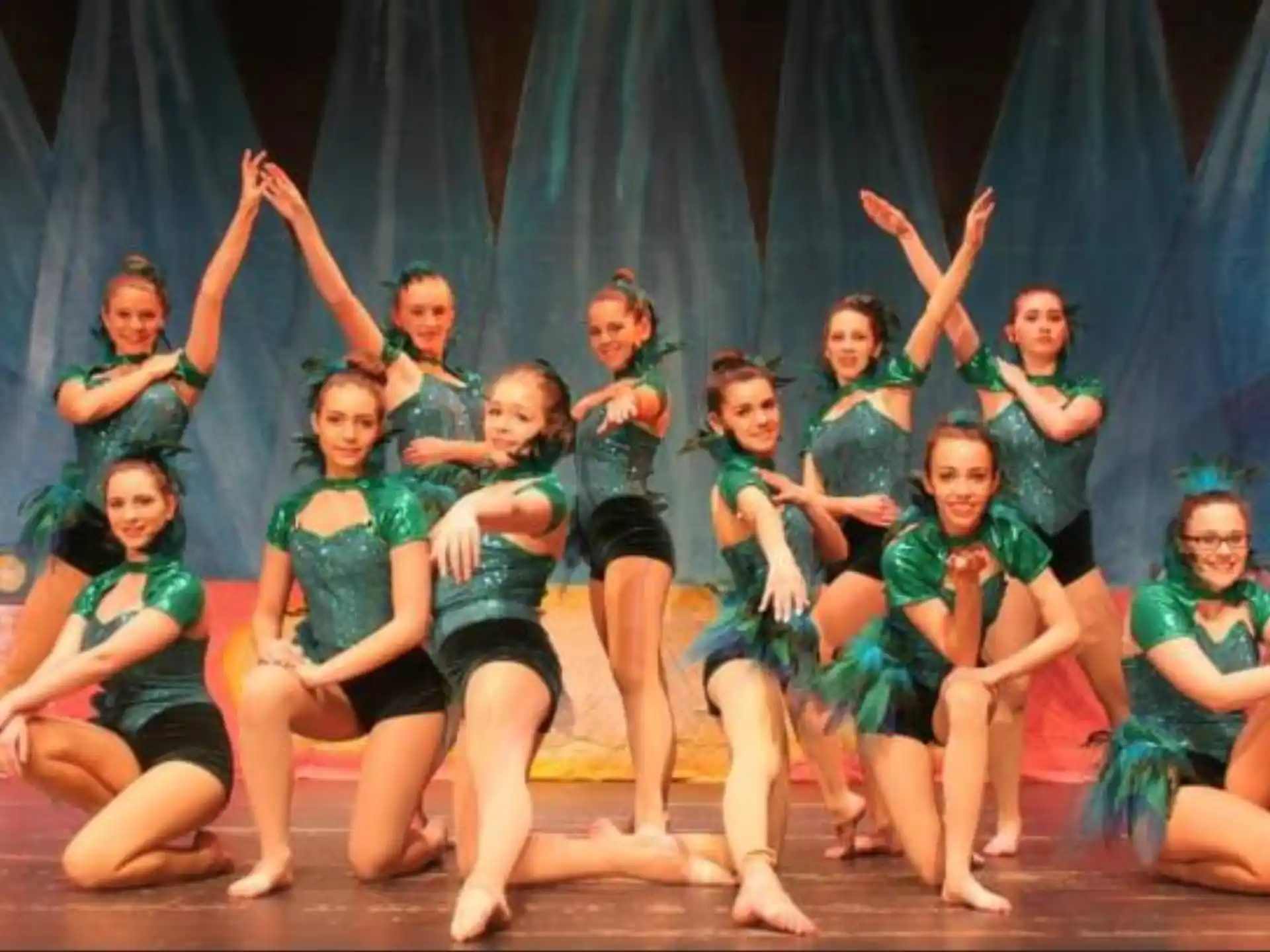 a group of girls in green and blue uniforms on a stage