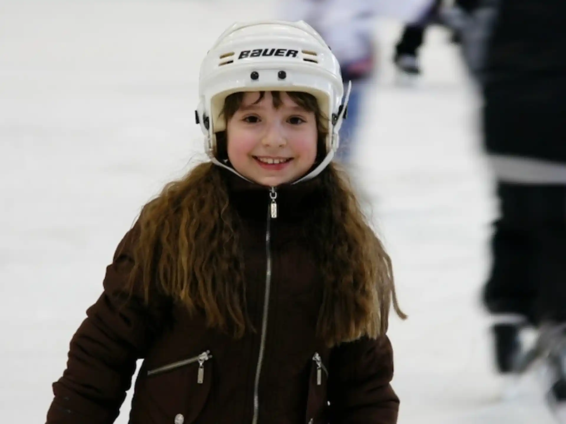 a girl wearing a helmet and standing on ice