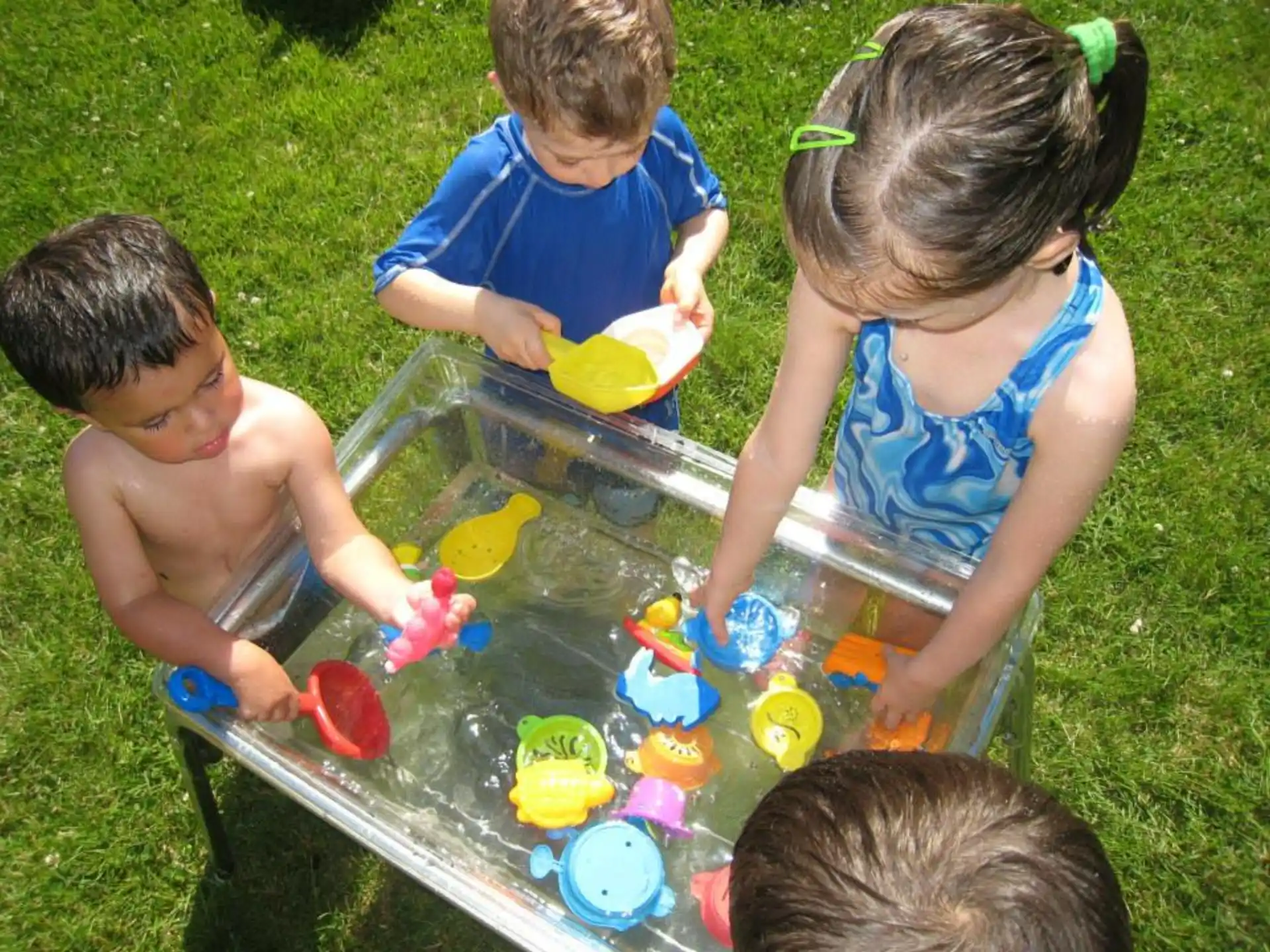 a group of kids playing in a plastic tub of water