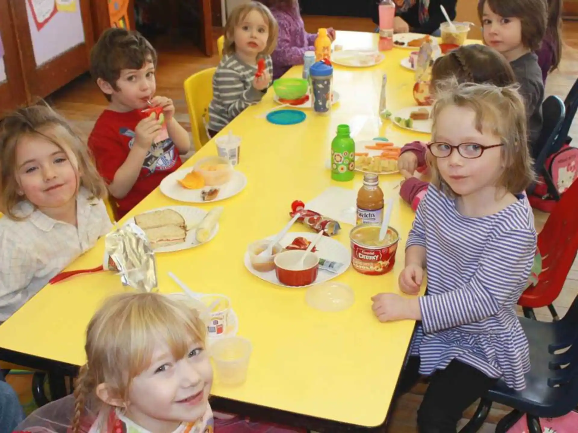 a group of children sitting at a table eating food
