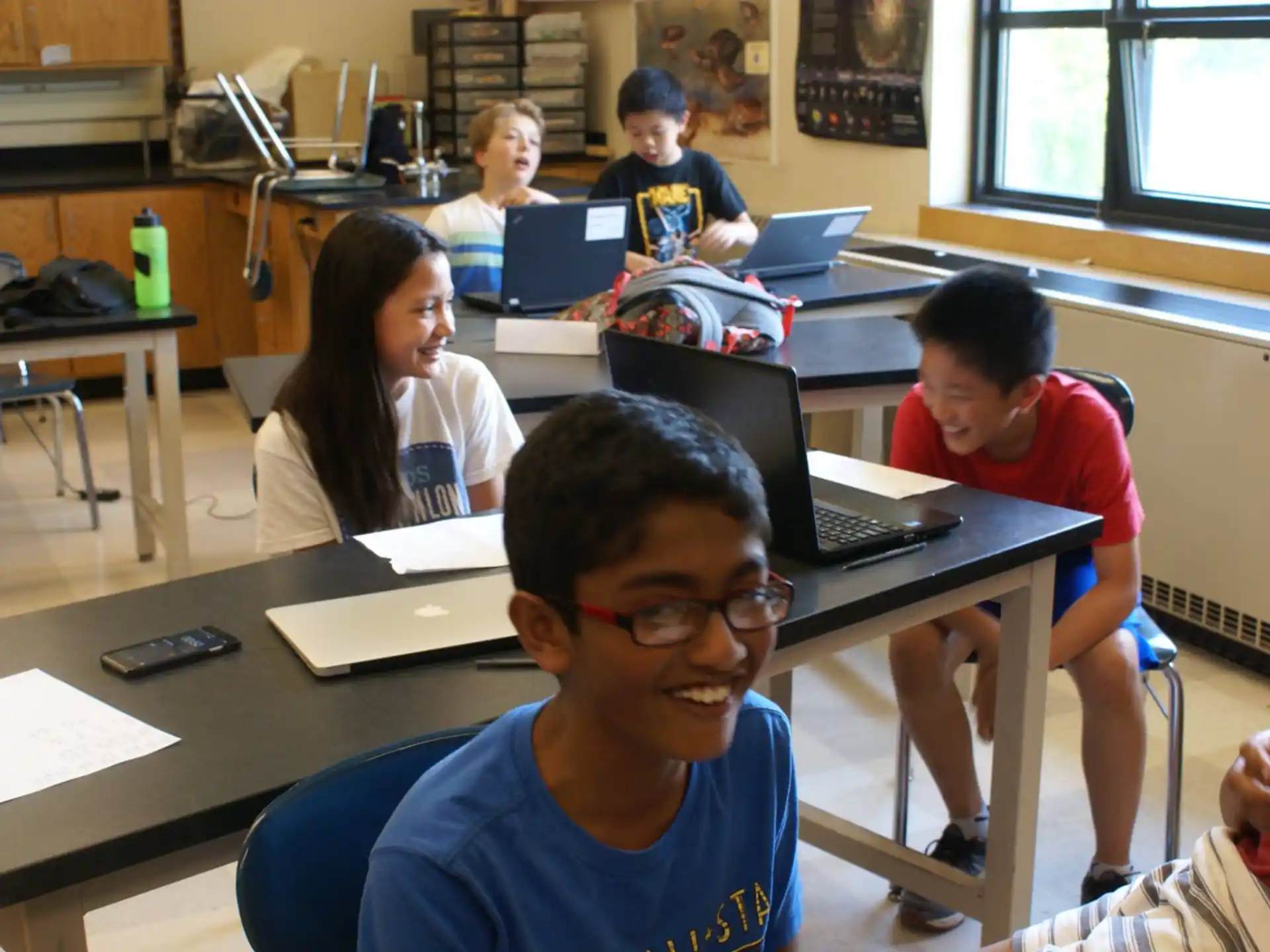 a group of people sitting at desks with laptops