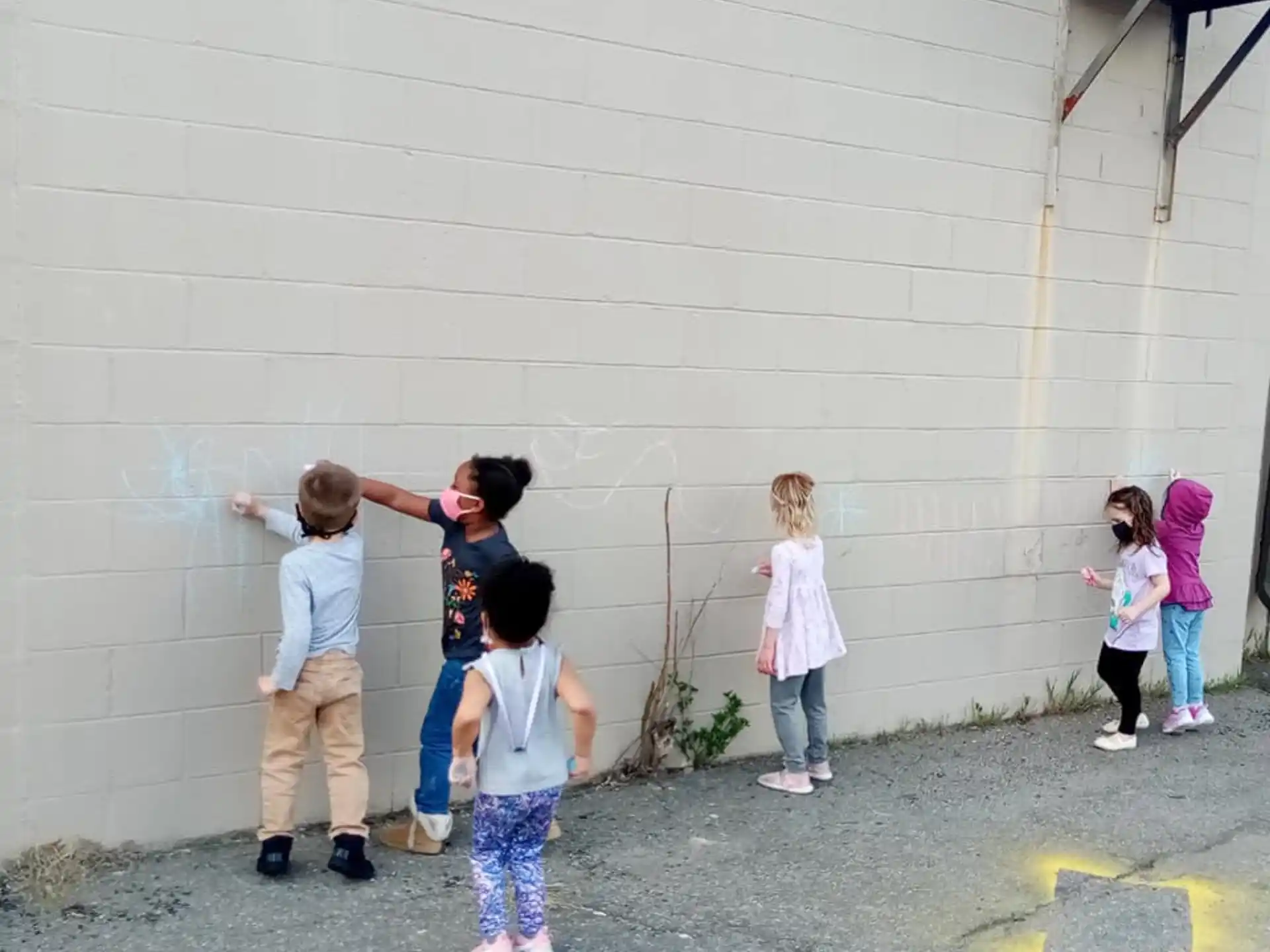 a group of children standing in front of a white wall