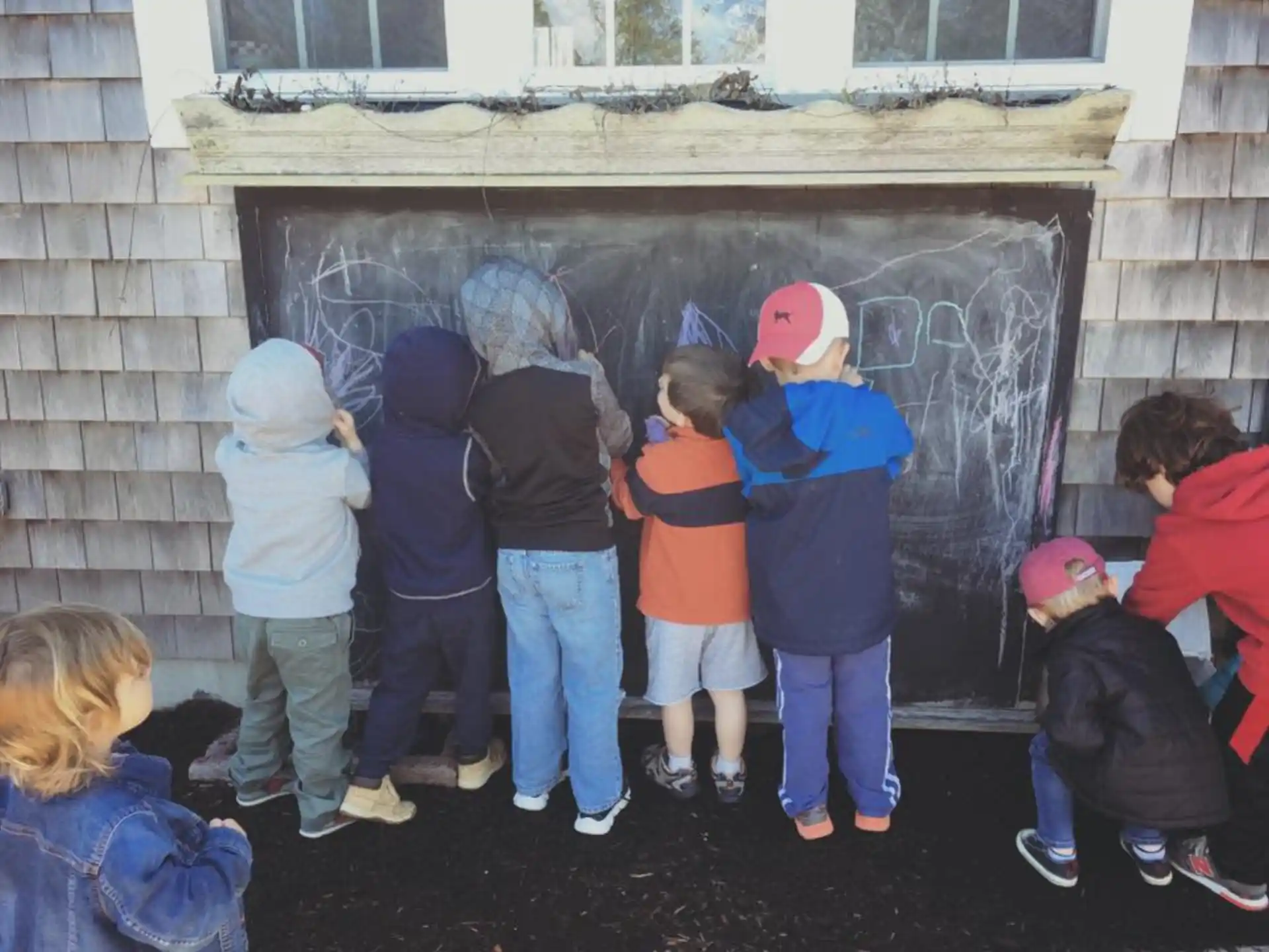 a group of children looking at a painting on a wall