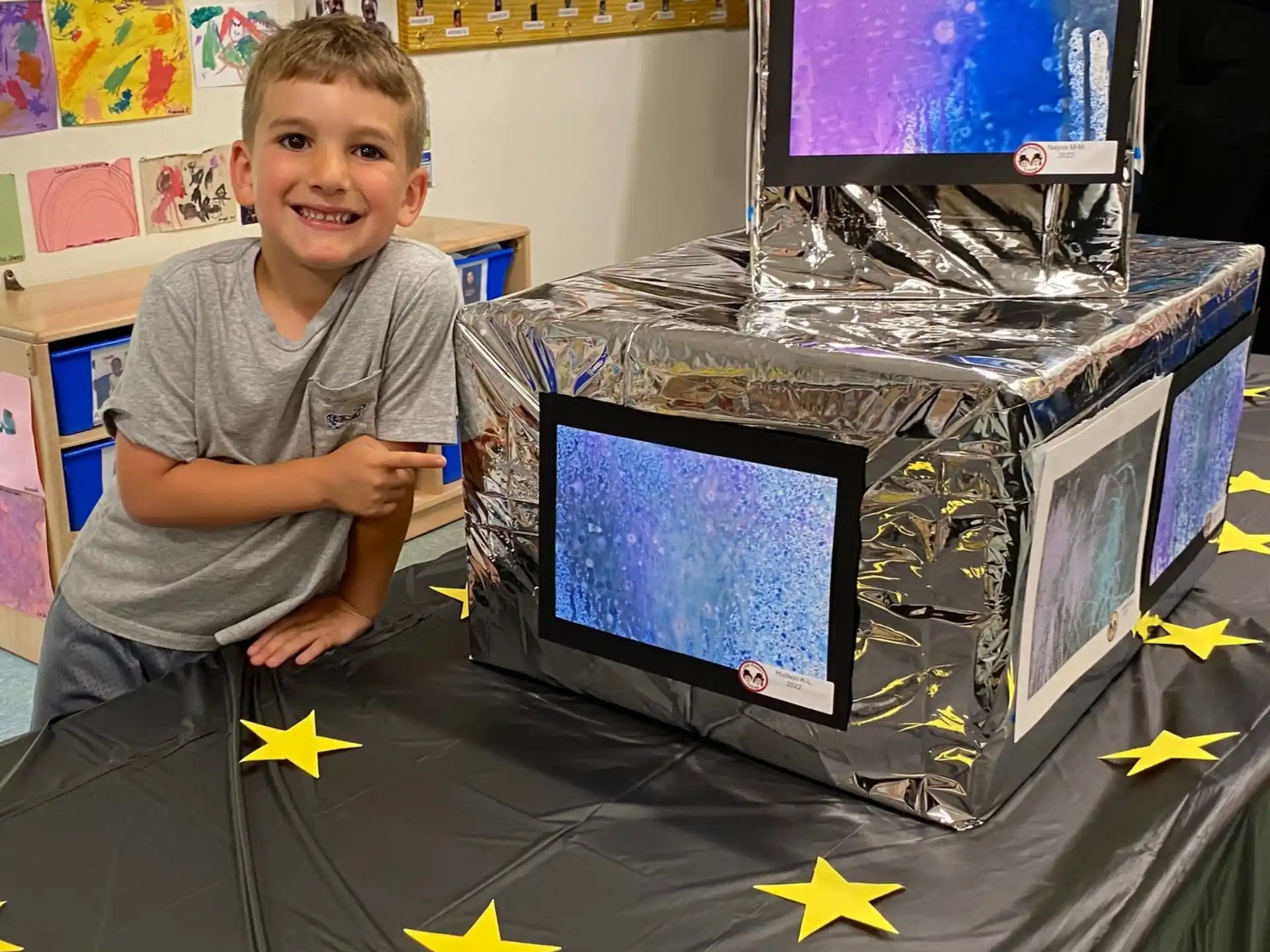 a boy sitting next to a computer