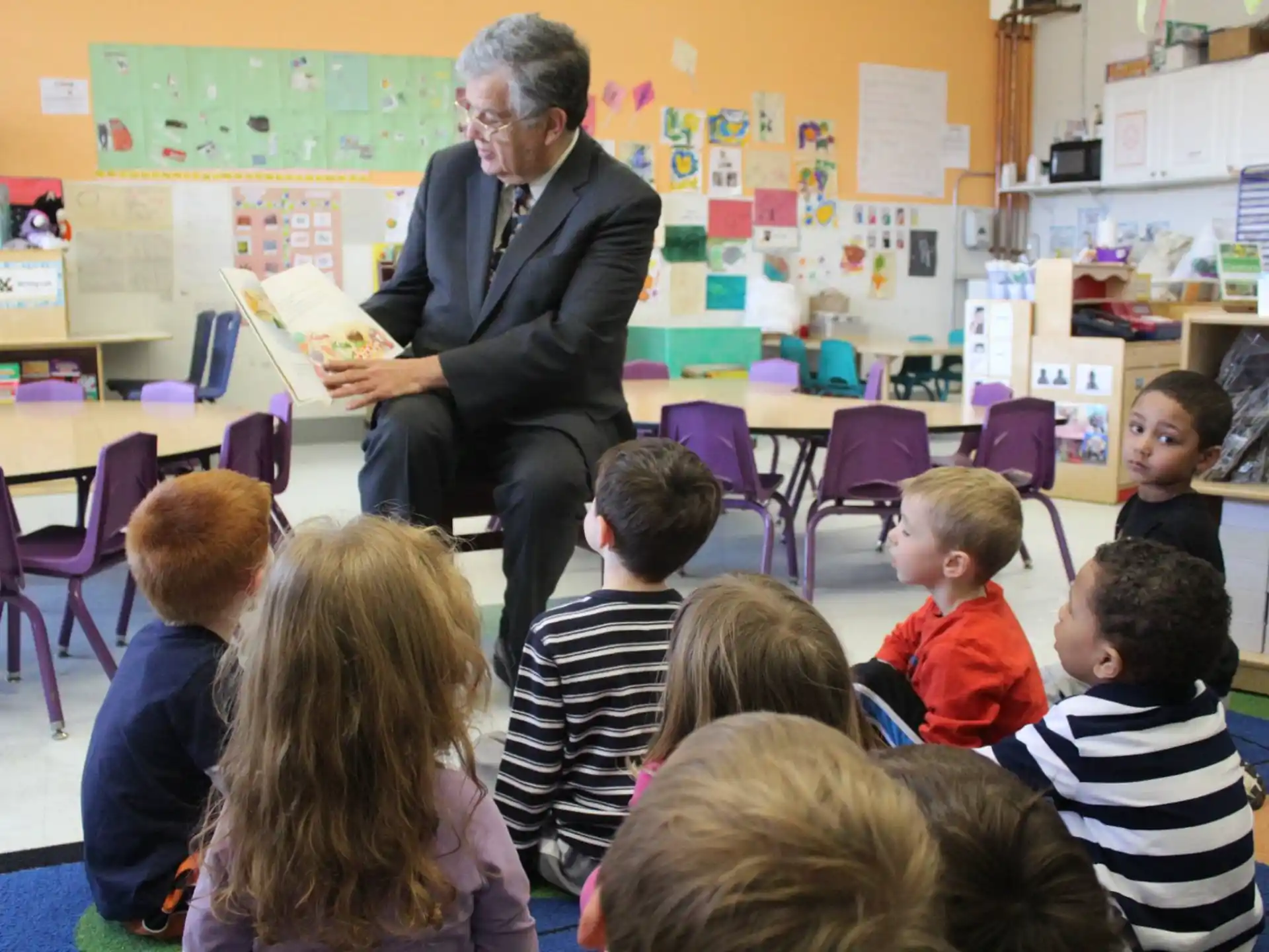 a person reading a book to a group of children